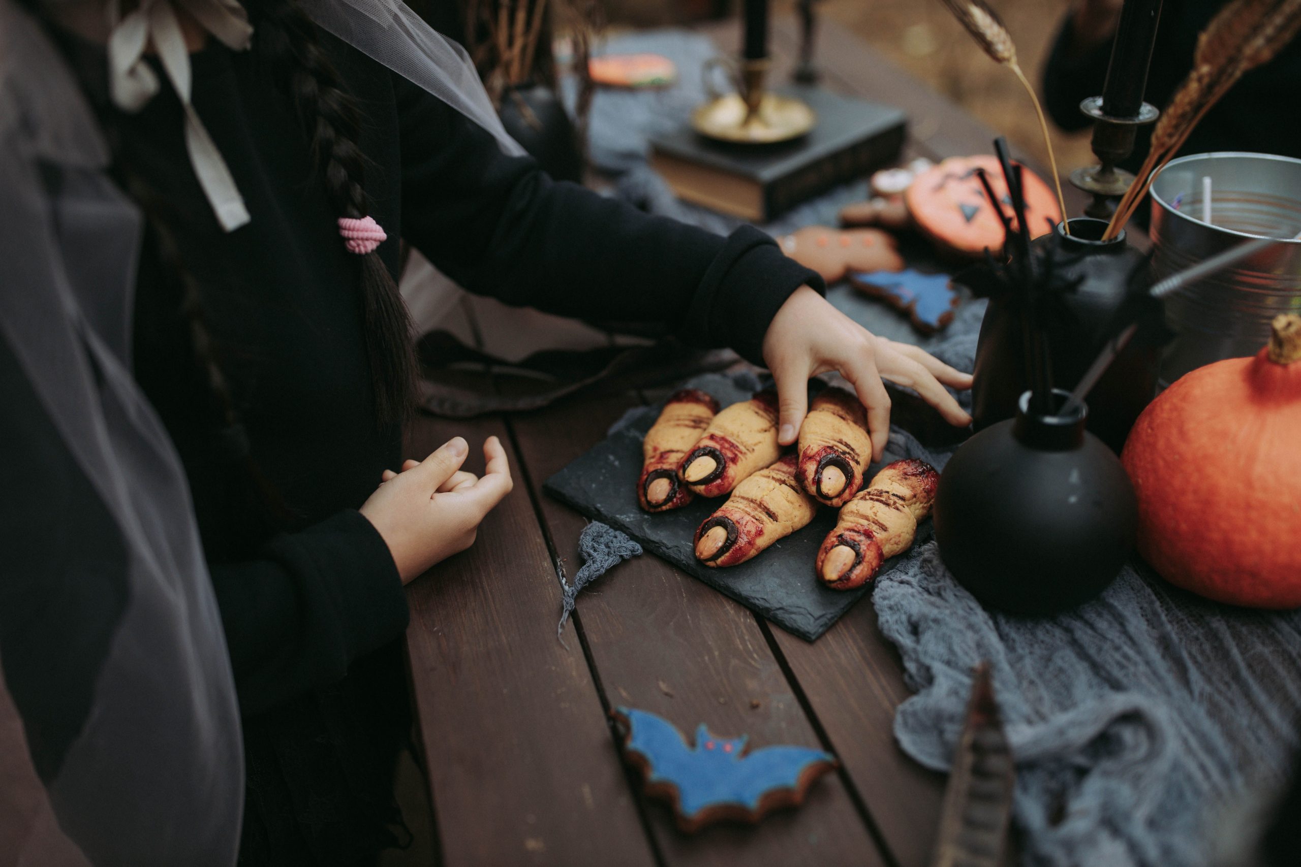 Close-up of Halloween-themed treat table with finger-shaped cookies and pumpkins.