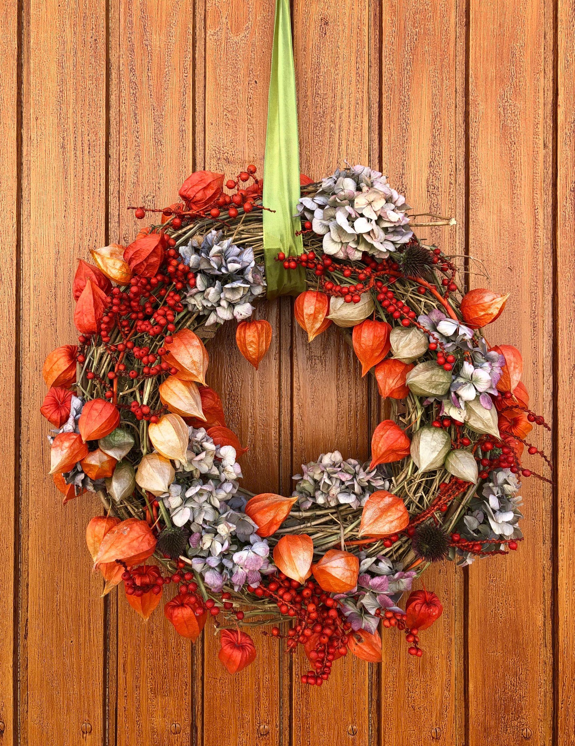 Colorful decorative wreath with autumn hues hanging on a wooden door.