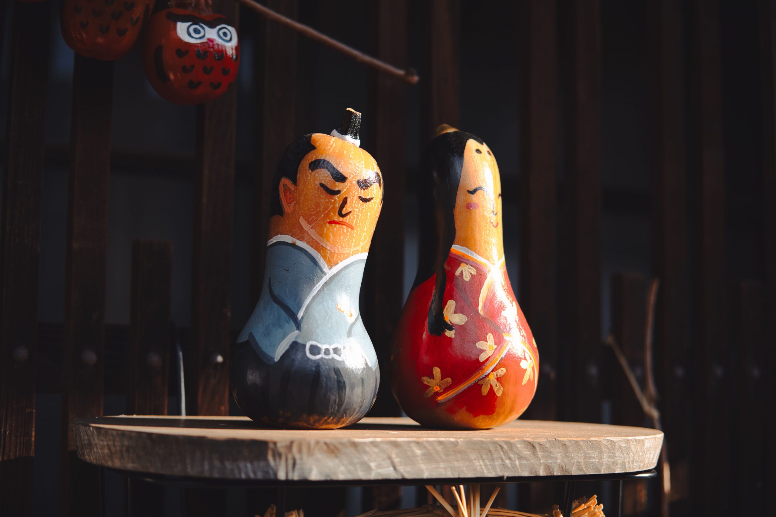 Colorful painted gourds depicting traditional Japanese characters on a wooden shelf.