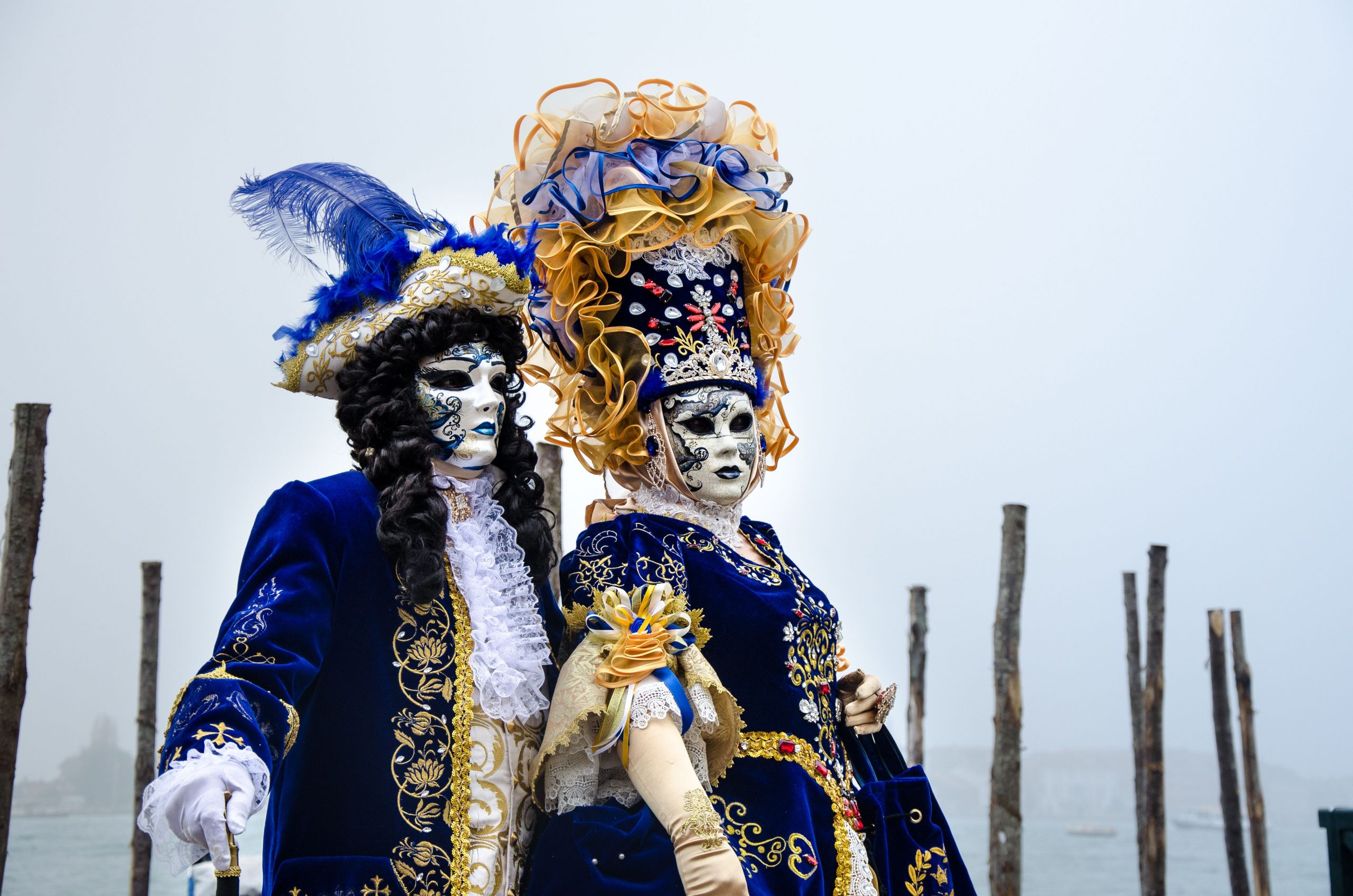 Couple in elaborate Venetian costumes at a traditional masquerade event, showcasing exquisite craftsmanship.