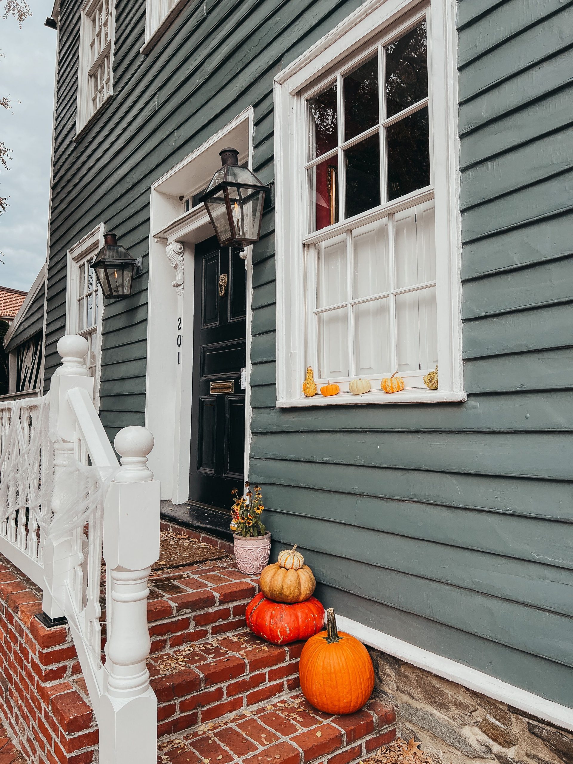 Cozy autumn porch scene with pumpkins, lanterns, and a classic doorway, capturing seasonal warmth.