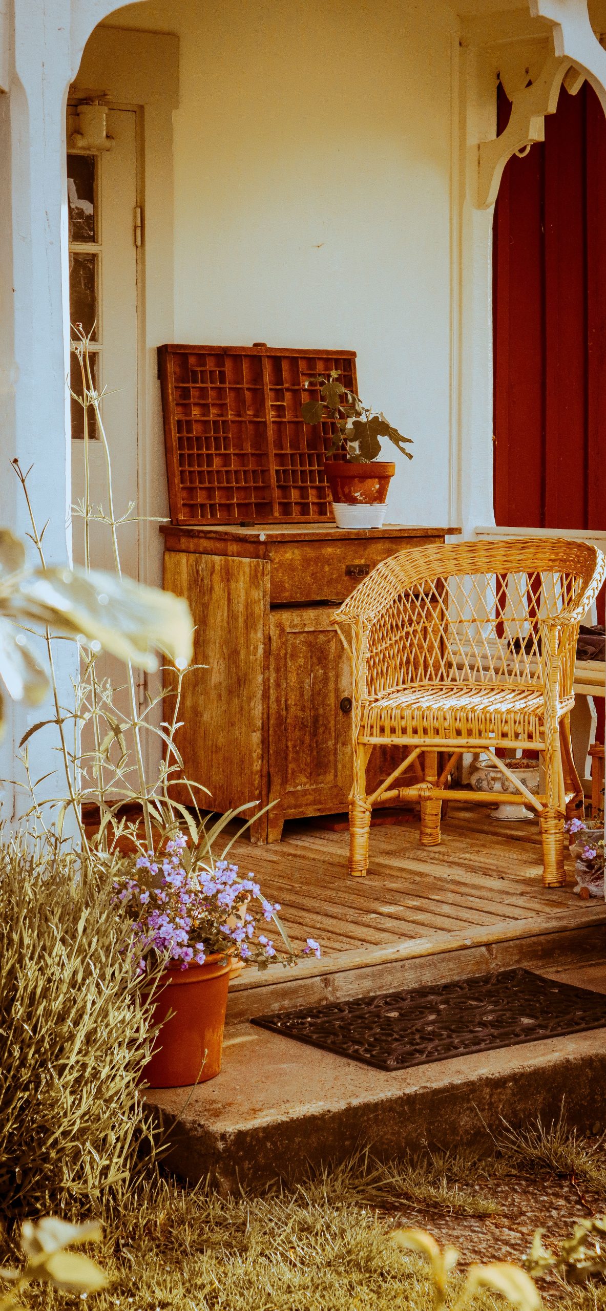 Cozy porch with a wicker armchair and wooden desk, perfect for relaxation at home.