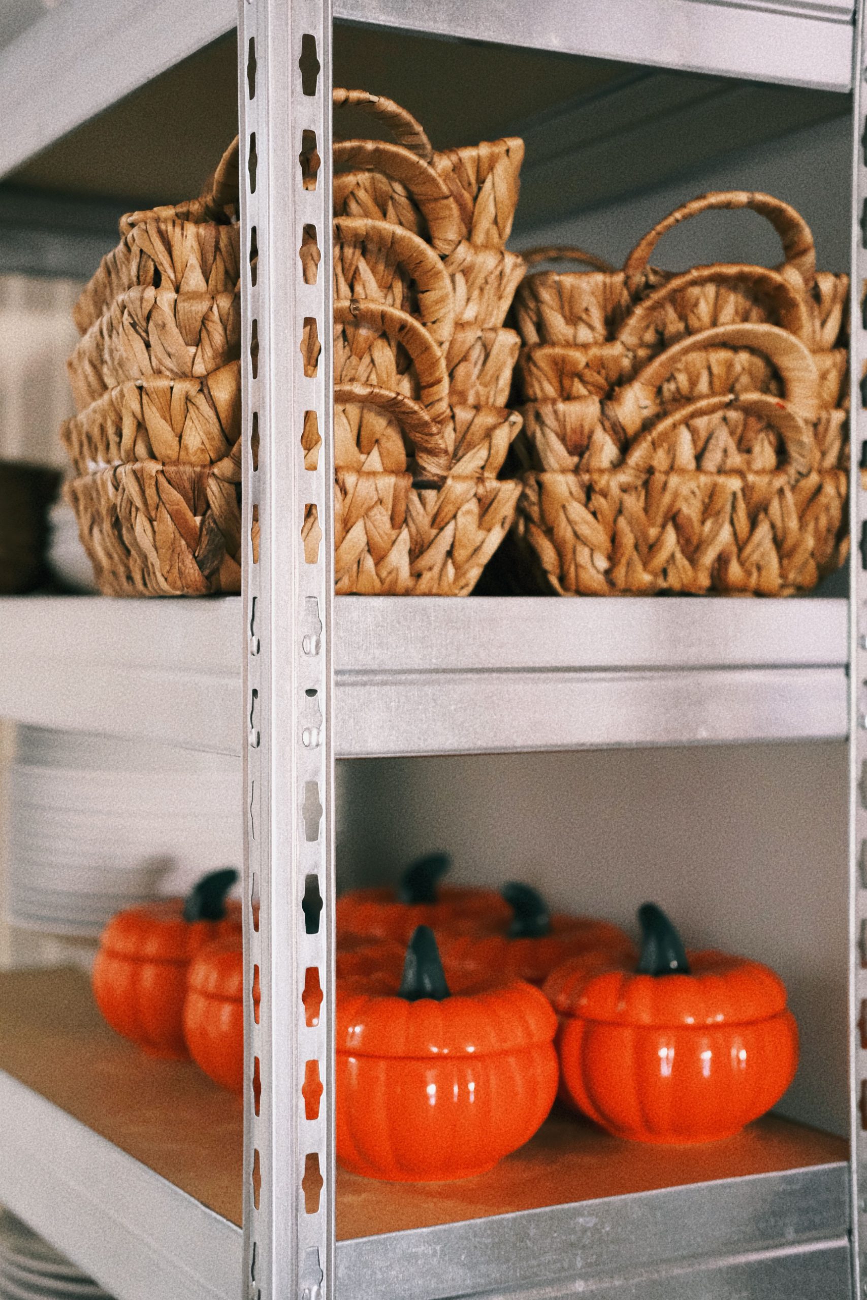 Decorative pumpkin-shaped containers and wicker baskets neatly arranged on metal shelves.