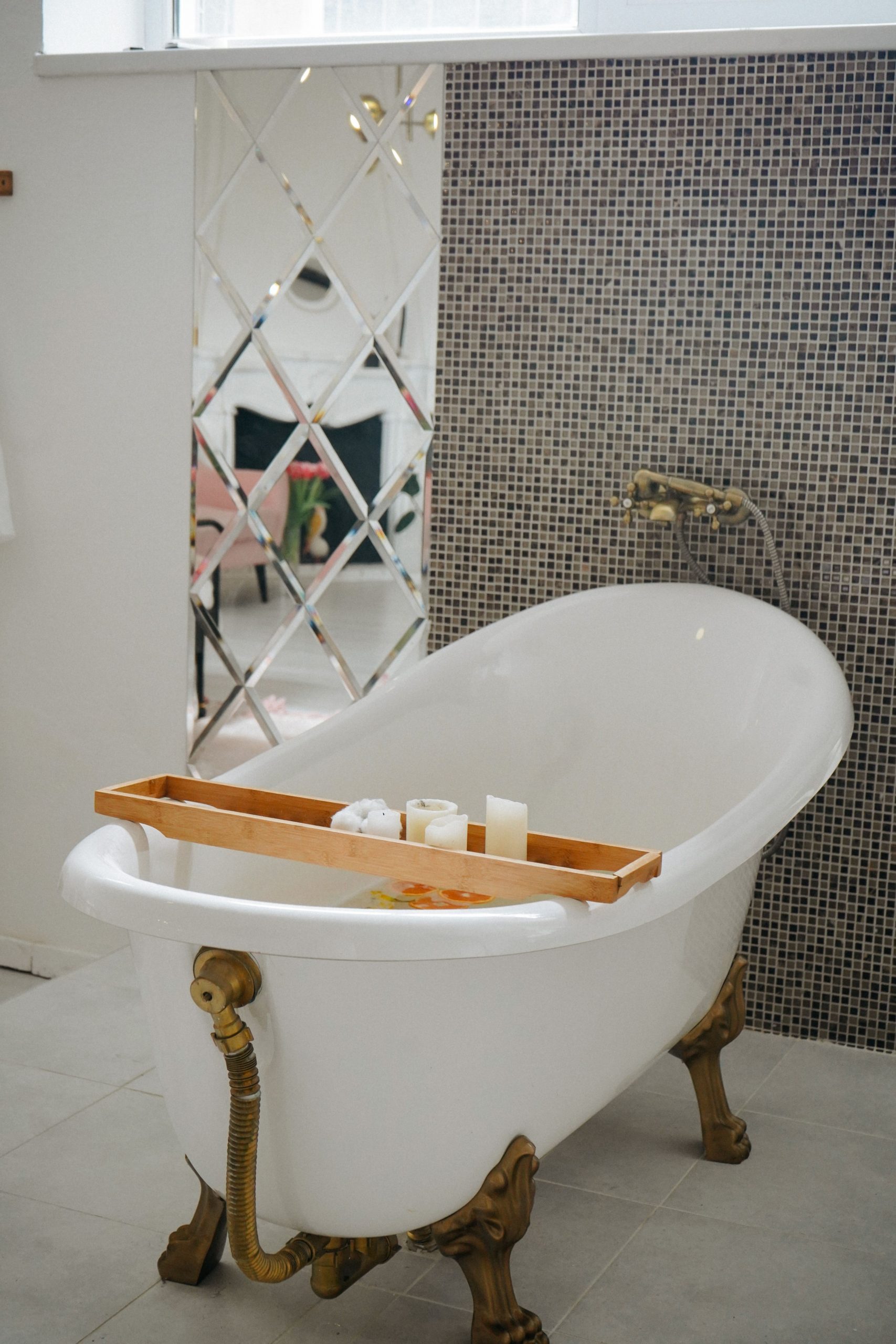 Elegant bathroom featuring a freestanding tub, mosaic wall, and decorative candles for a relaxing atmosphere.