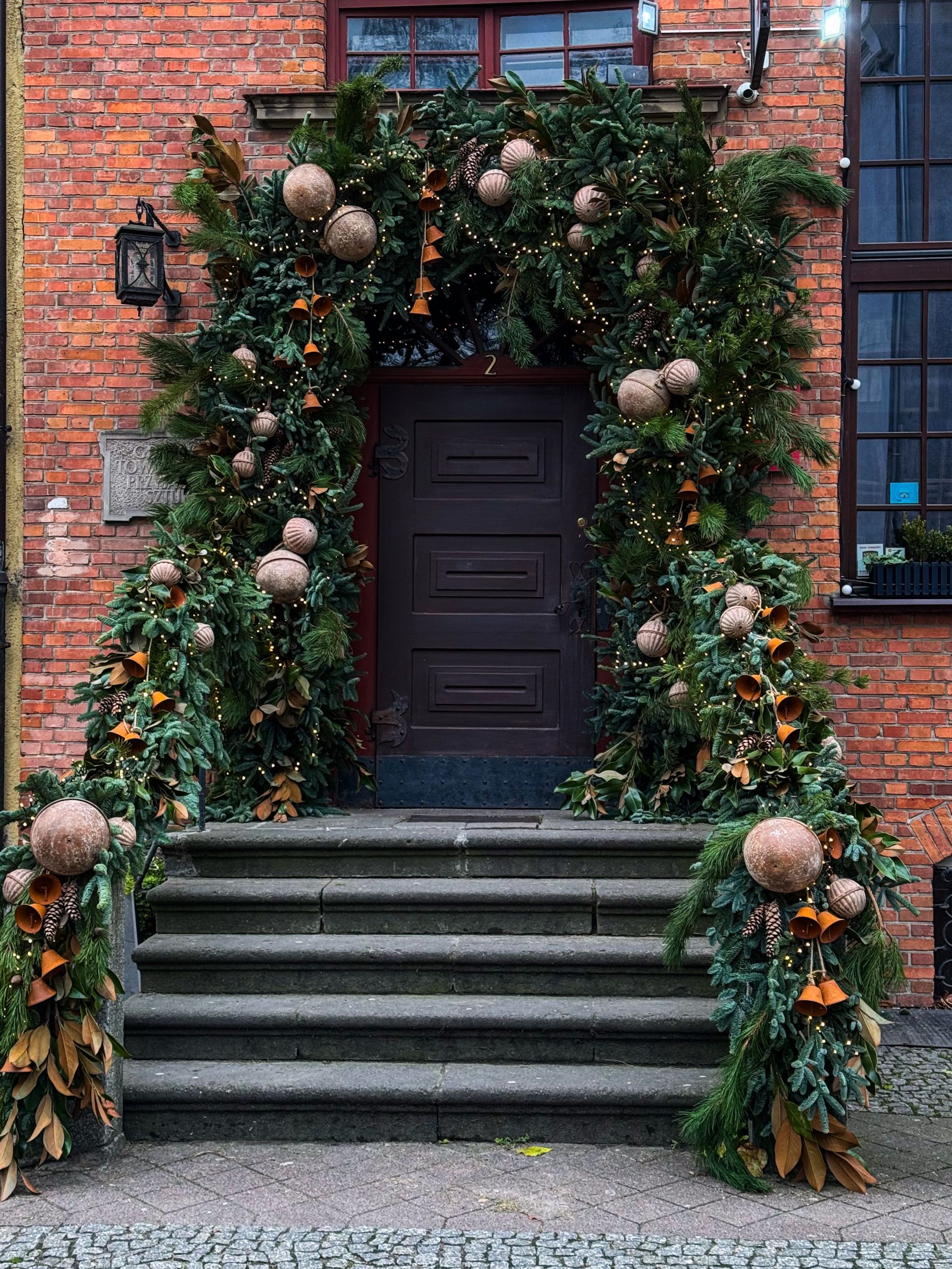 Elegant doorway adorned with festive Christmas decorations, lush greenery, and ornaments.