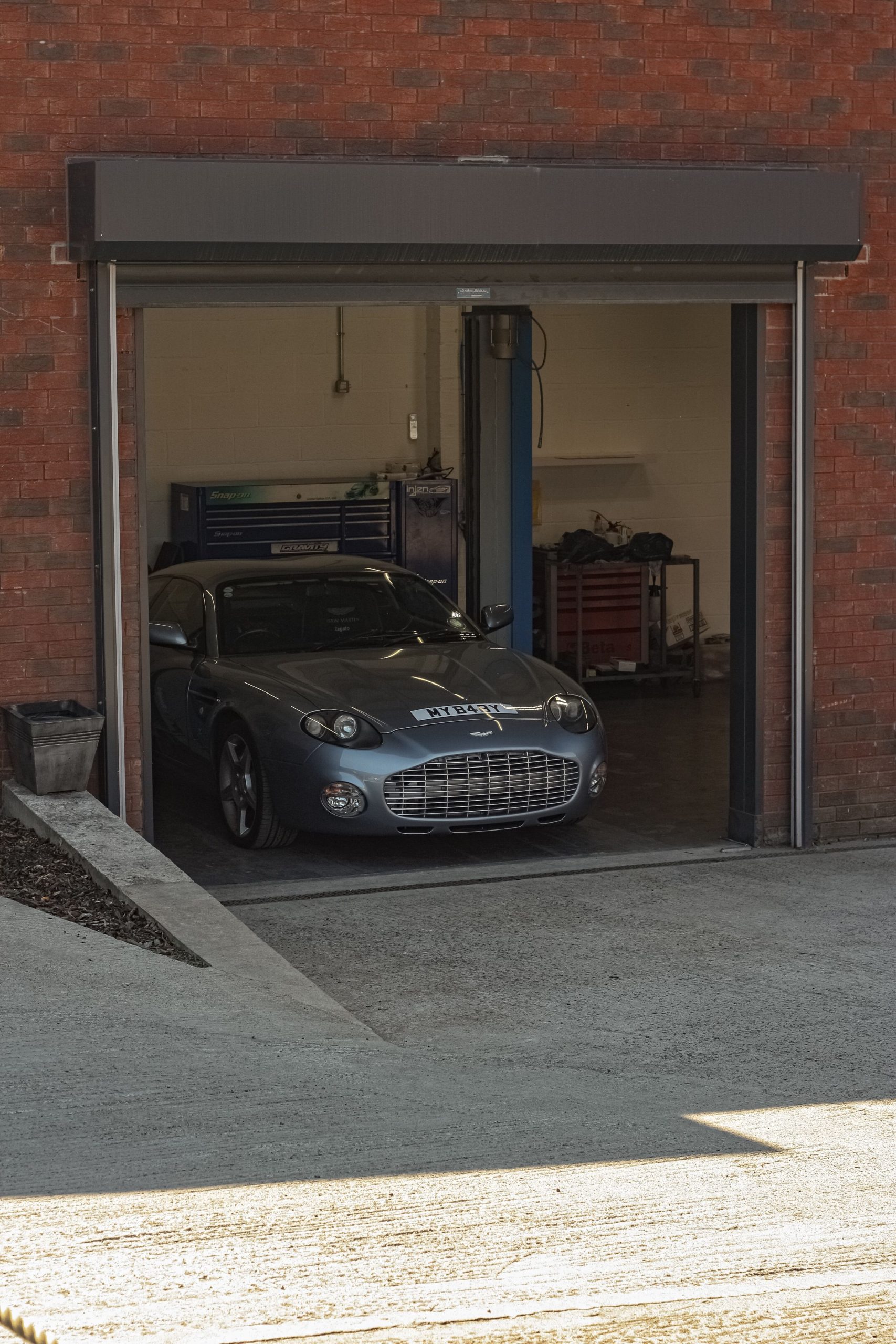 Elegant sports car parked inside a brick-walled garage, ready for service.