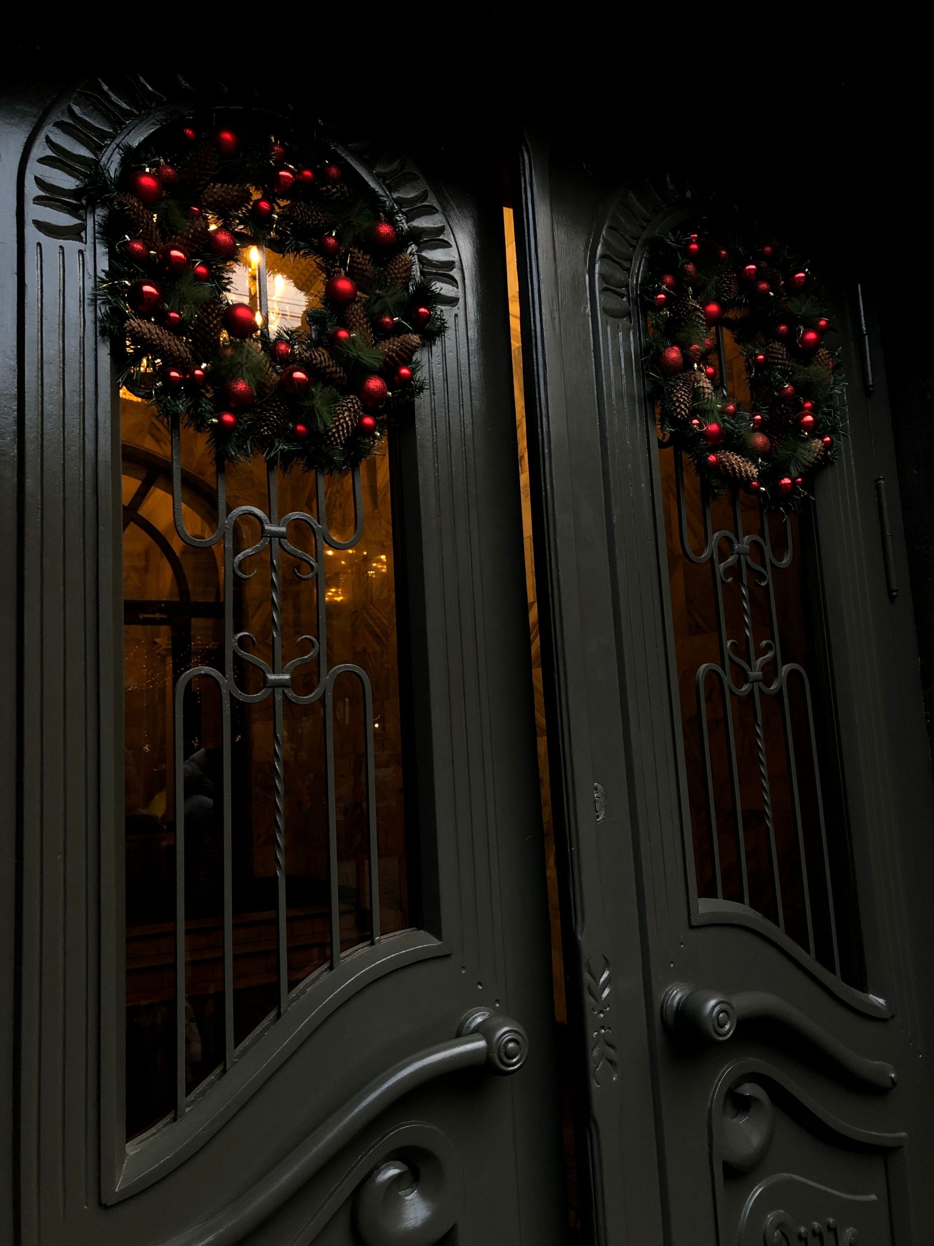 Festive Christmas wreaths with baubles adorn elegant double doors, creating a warm holiday atmosphere.