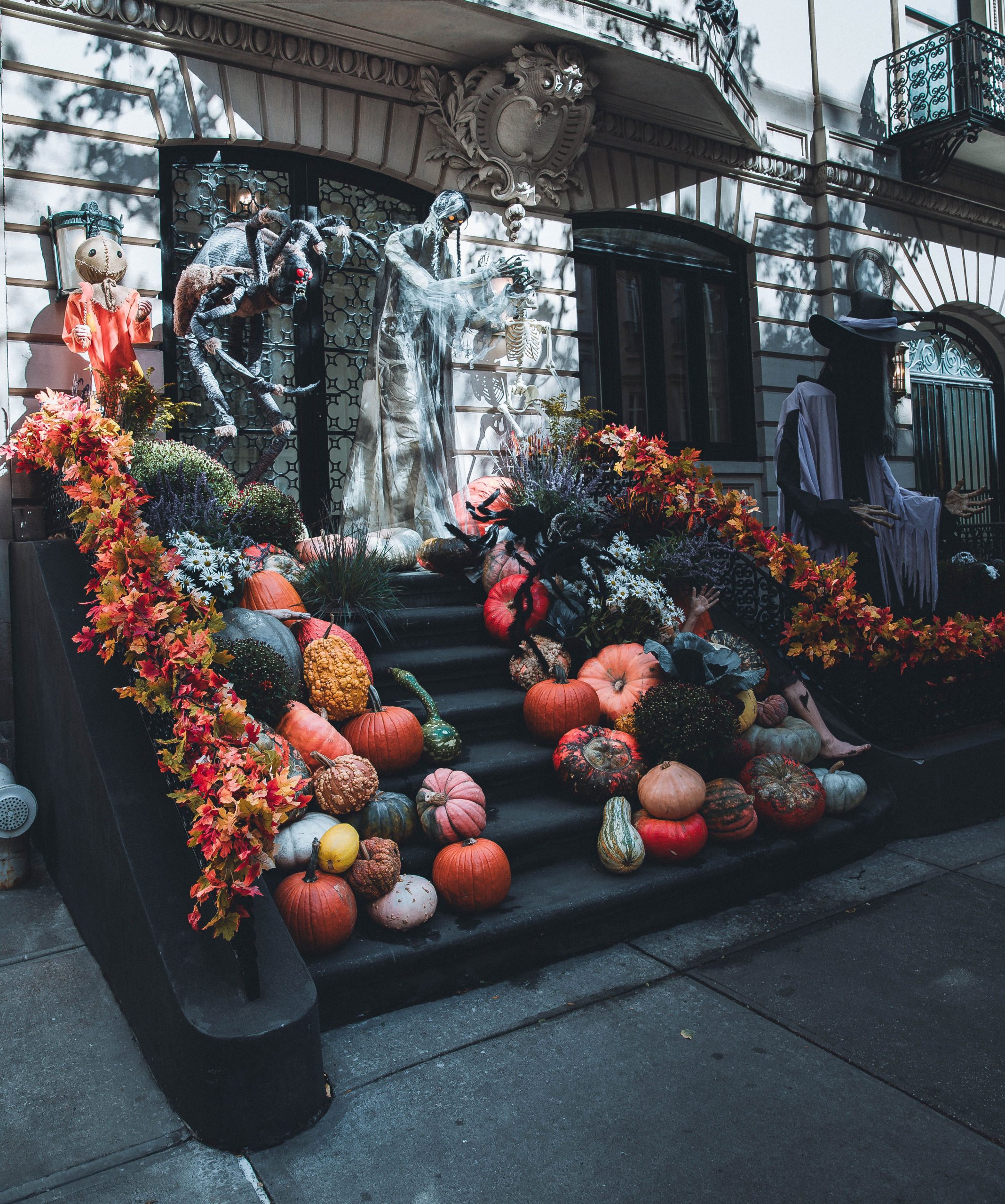 Festive Halloween decorations on a brownstone staircase in New York with pumpkins and fall leaves.