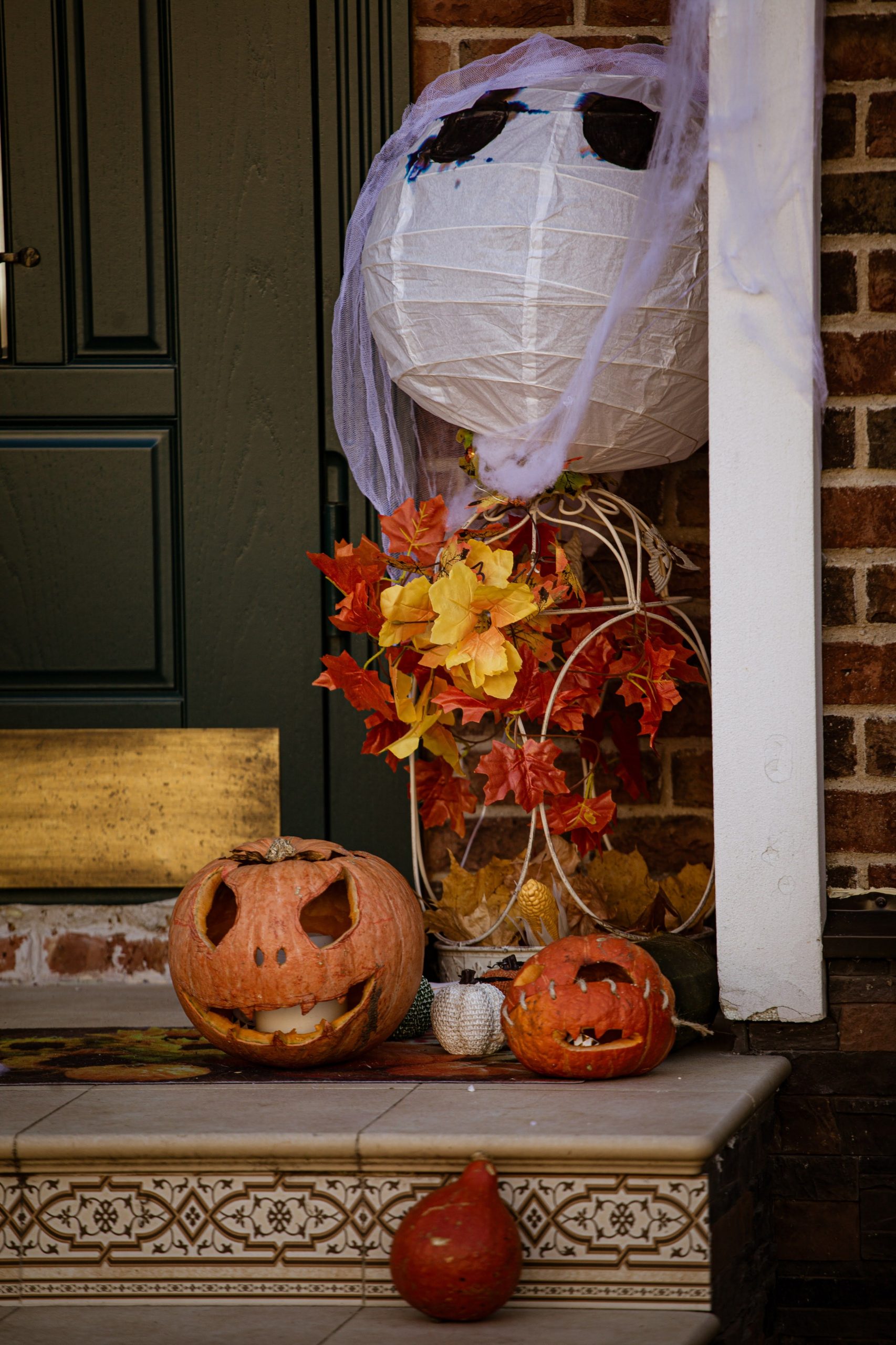 Festive Halloween scene with carved pumpkins and ghost decoration on a porch.