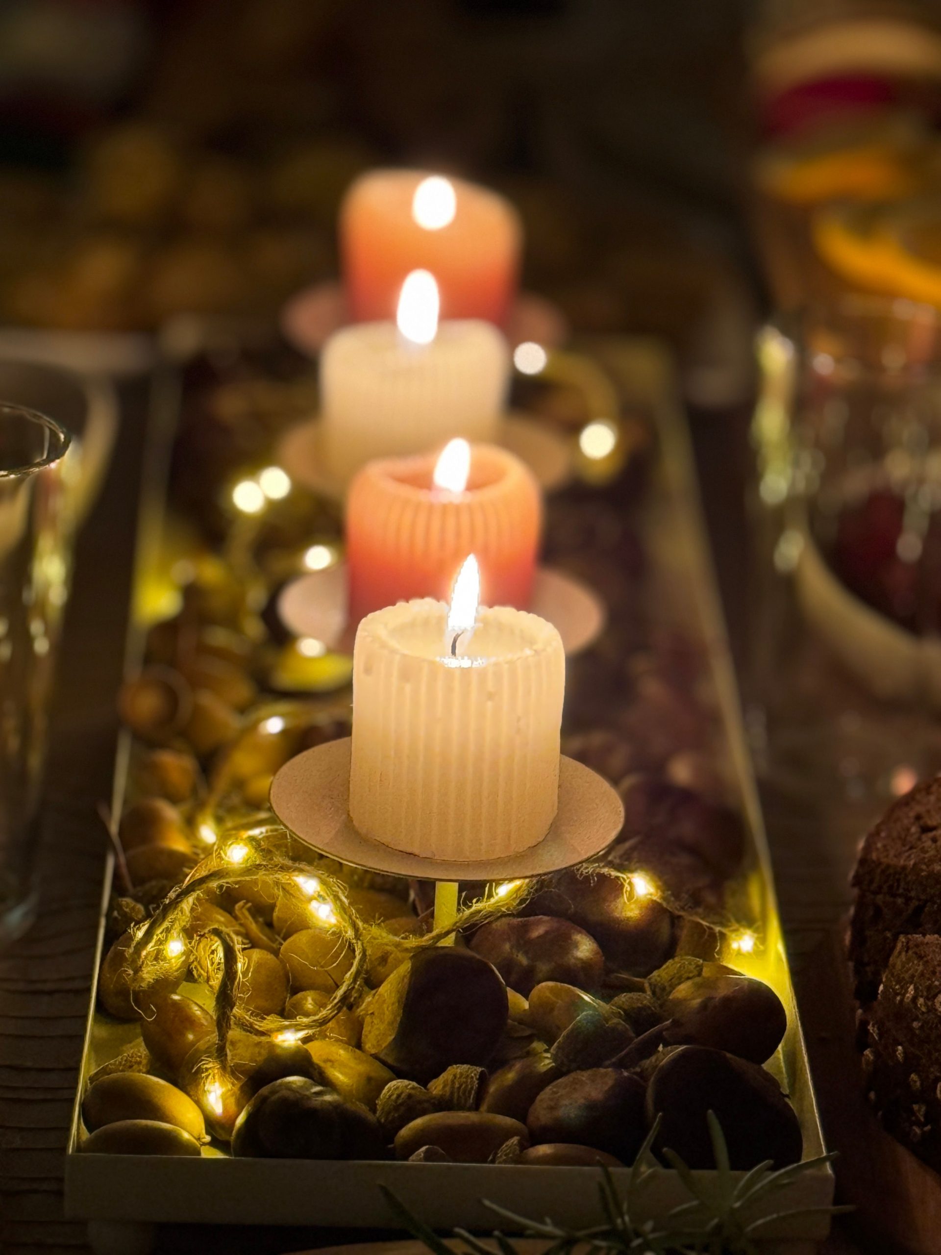 Four glowing candles with a rustic centerpiece create a cozy ambiance.
