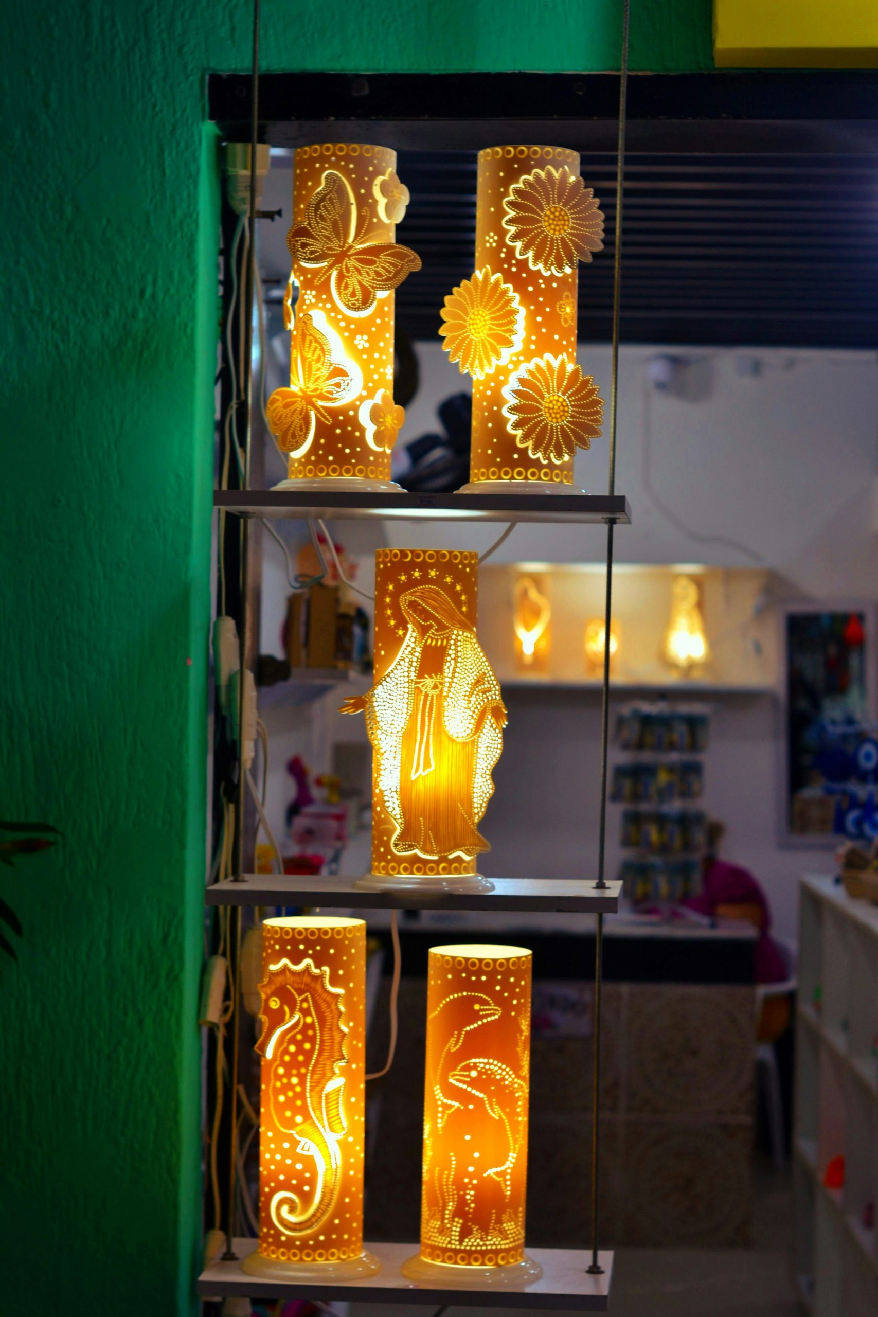 Four illuminated cylindrical lanterns with decorative cutouts.