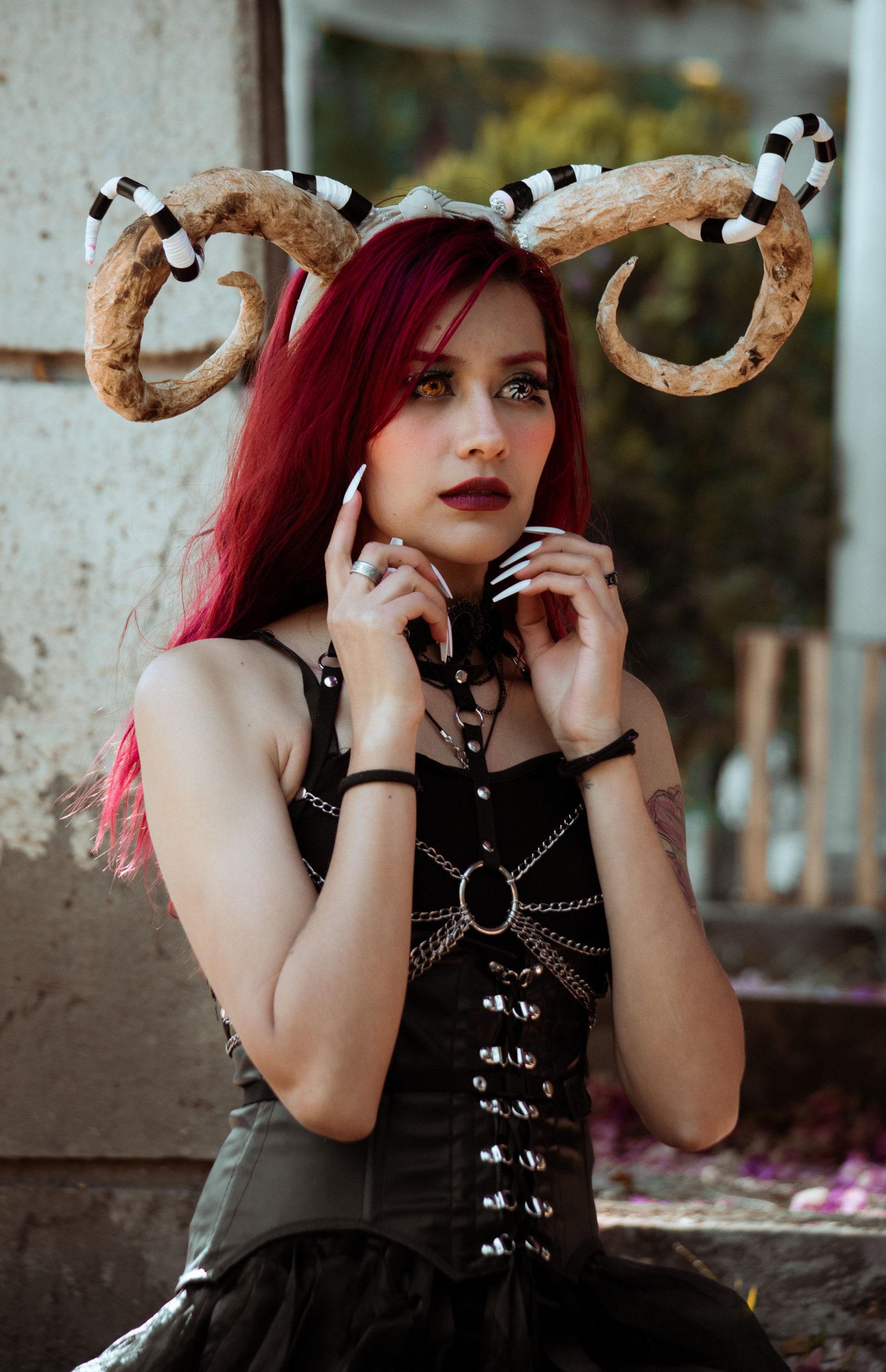 Gothic cosplay featuring intricate horn accessories and dark attire outdoors.