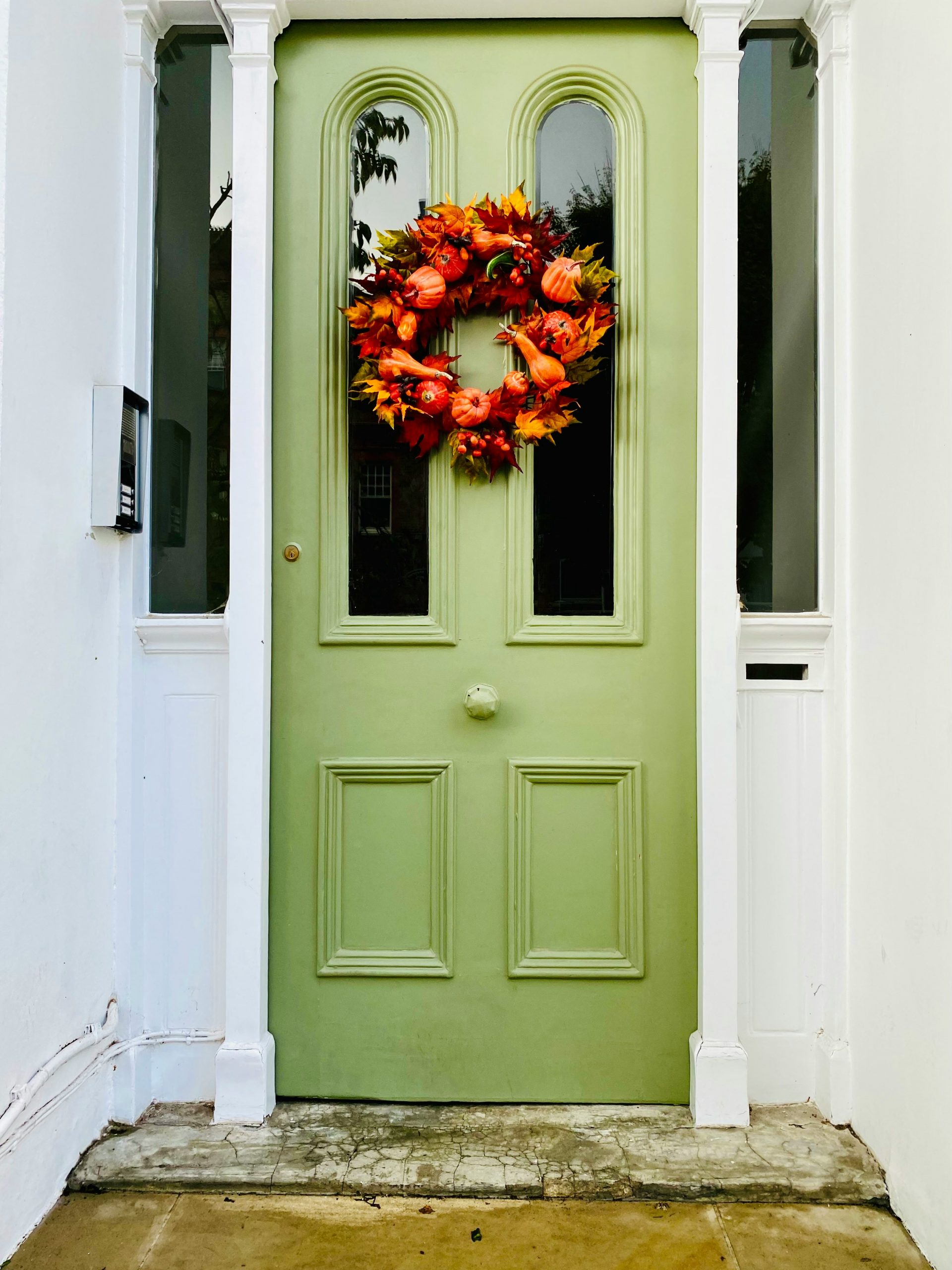 halloween decorations - autumn vibes on mint green front door with pumpkin and maple leaf wreath - fresh earth tones, ready for halloween