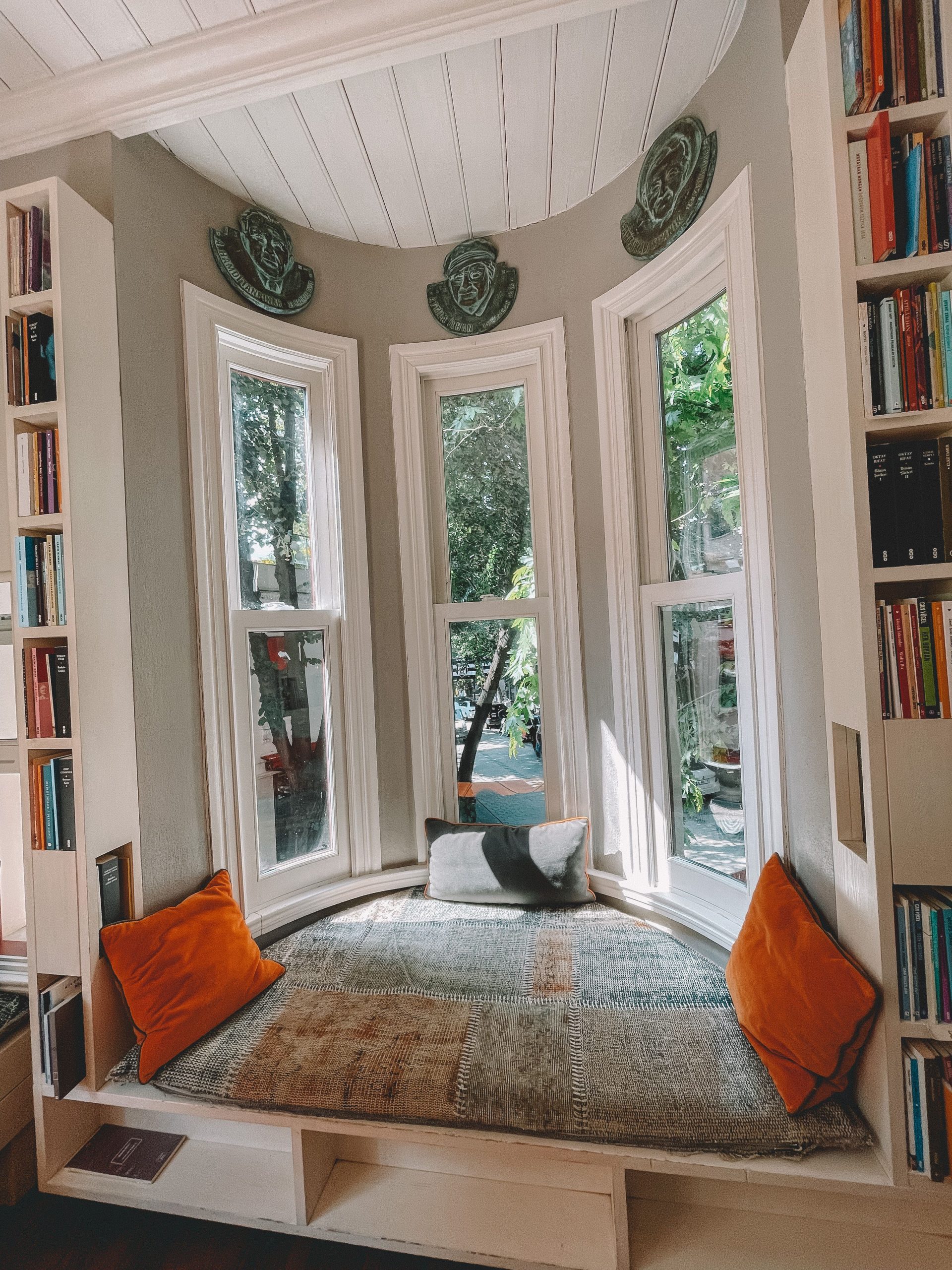 Inviting reading nook with natural light, cushions, and shelves in a stylish interior.