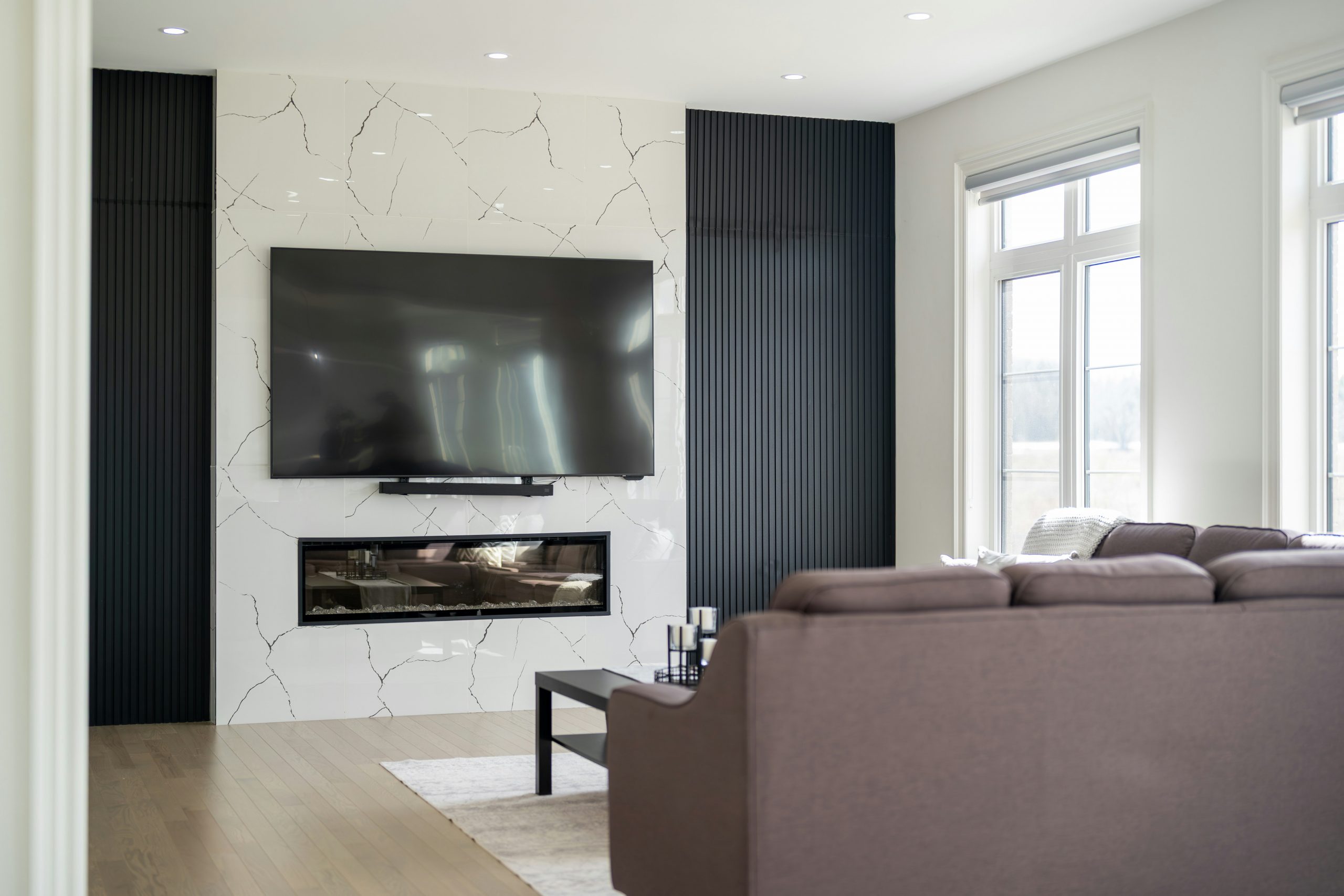 Modern living room with large television over fireplace.