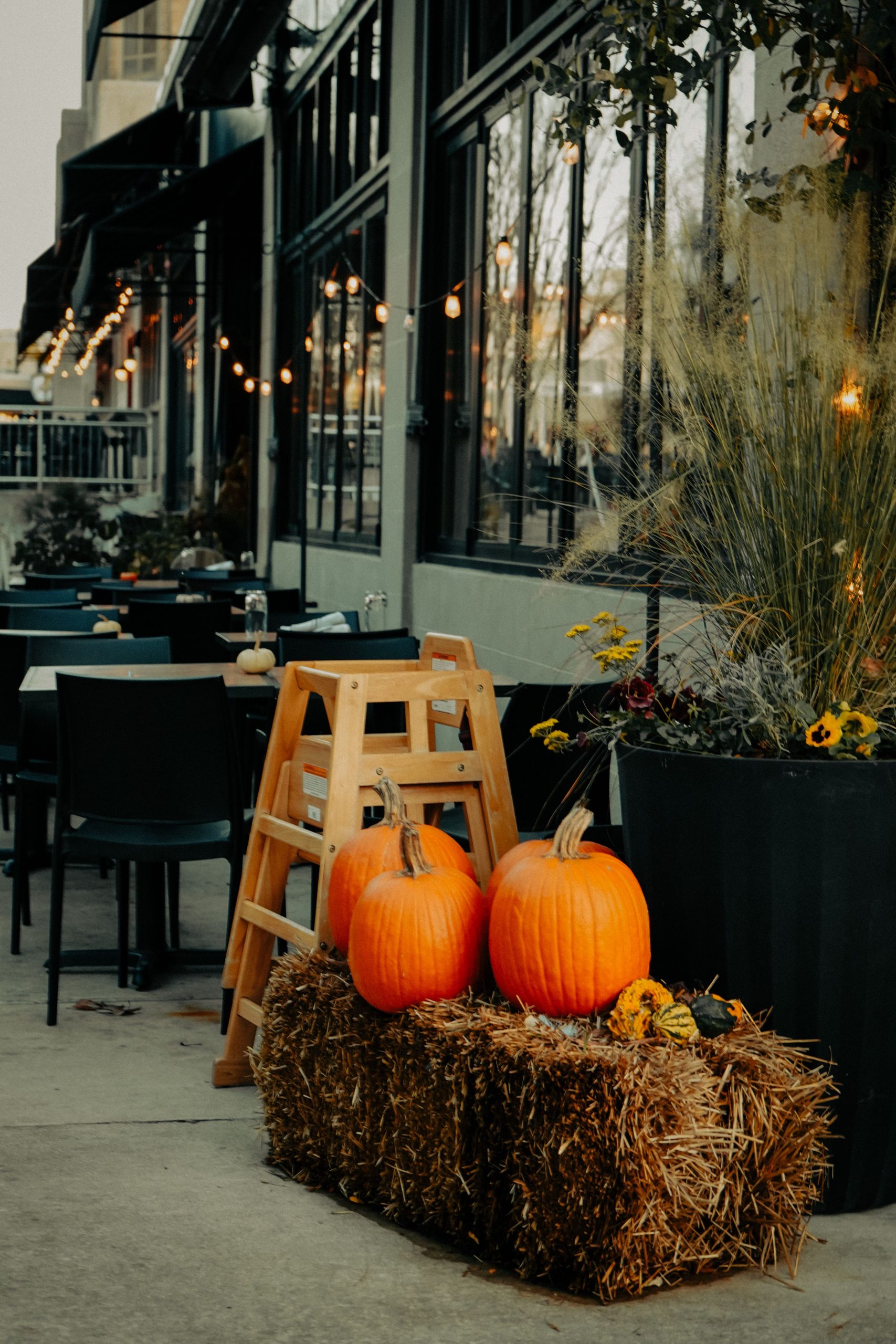 Outdoor cafe with pumpkins and hay bales, perfect autumn atmosphere.