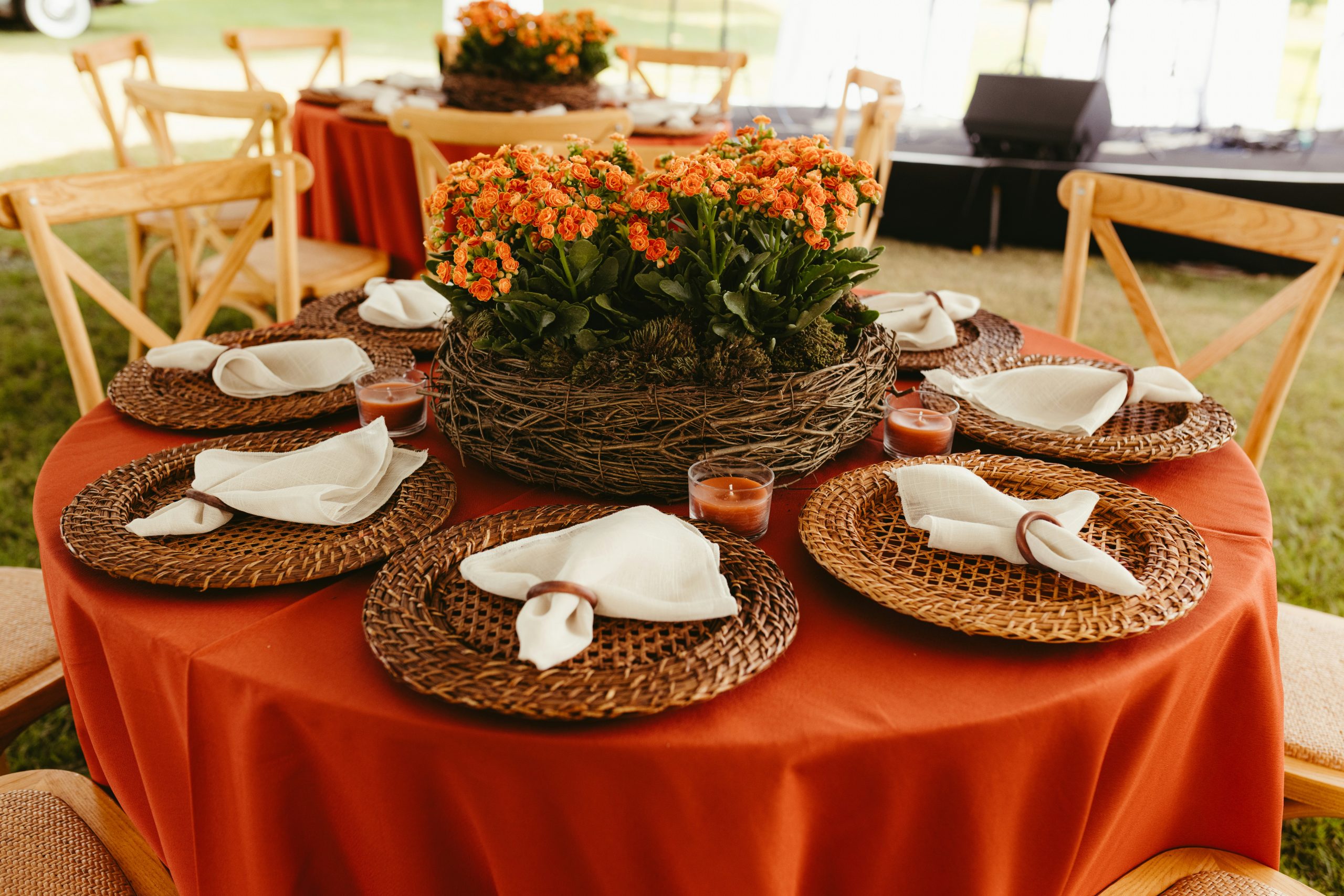 Red table setting with orange flower centerpiece and wooden chairs.