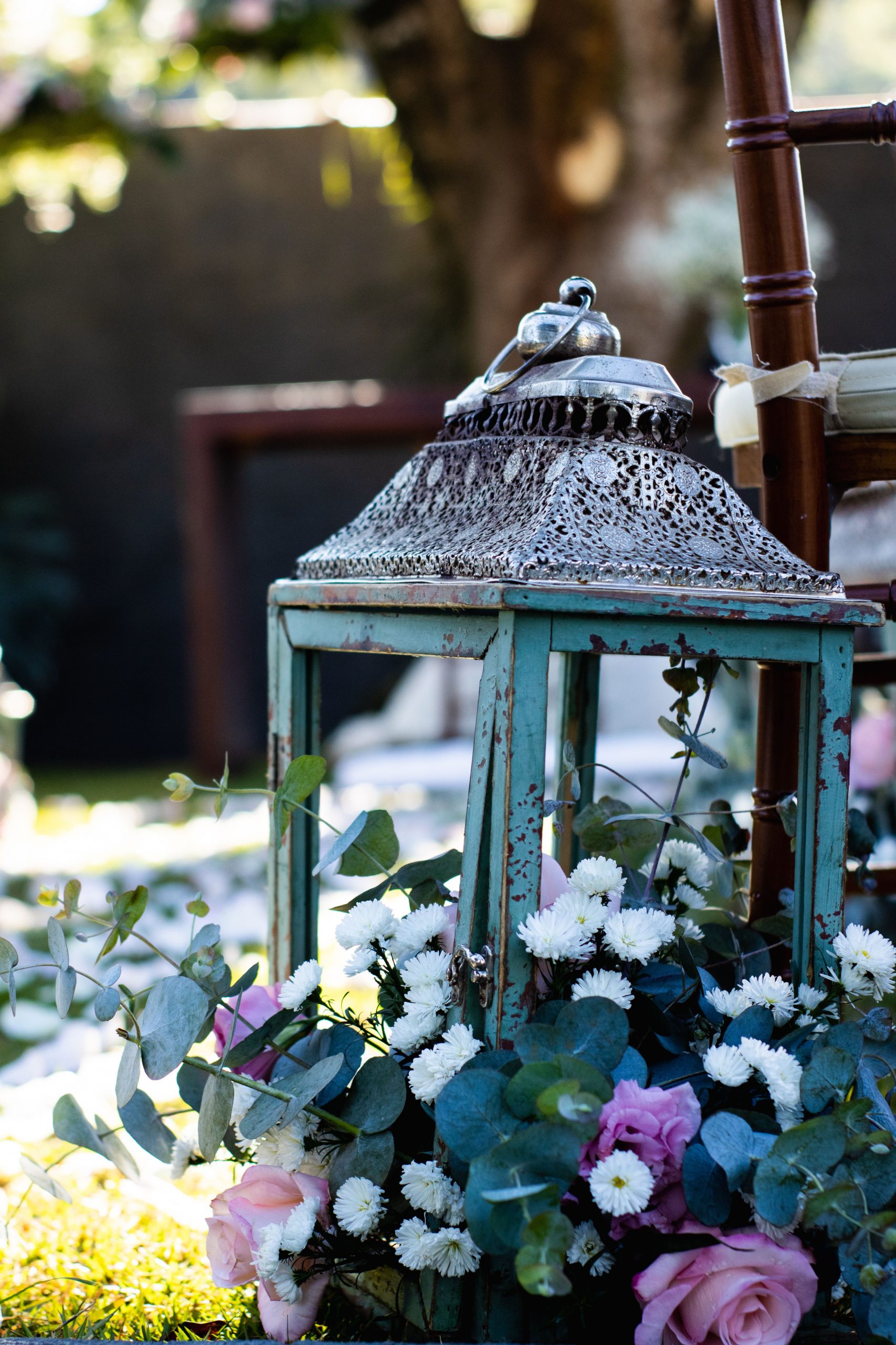 Rustic lantern surrounded by pink and white flowers in a picturesque garden setting.