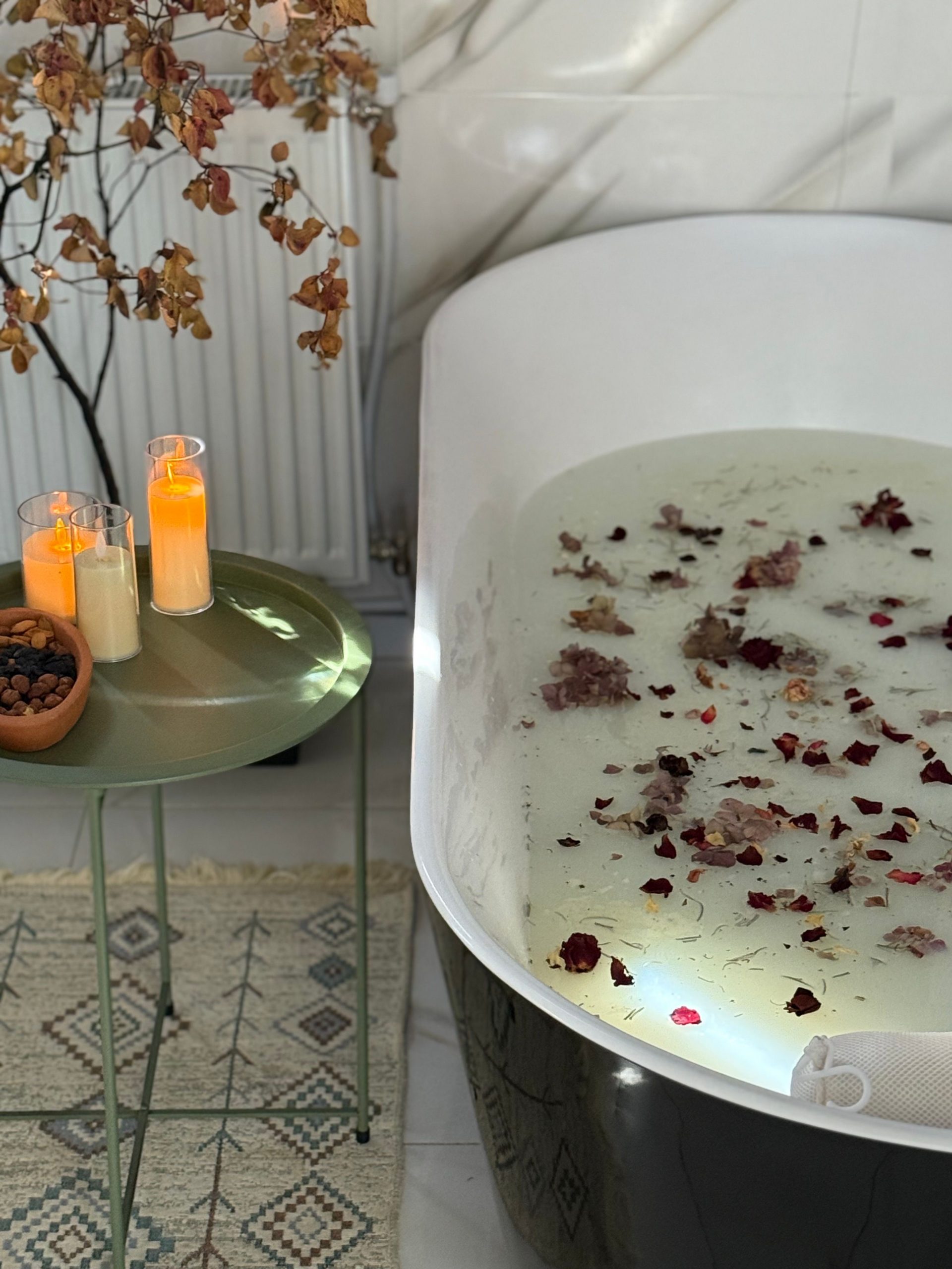 Serene bathtub filled with petals and lit candles, perfect for relaxation.