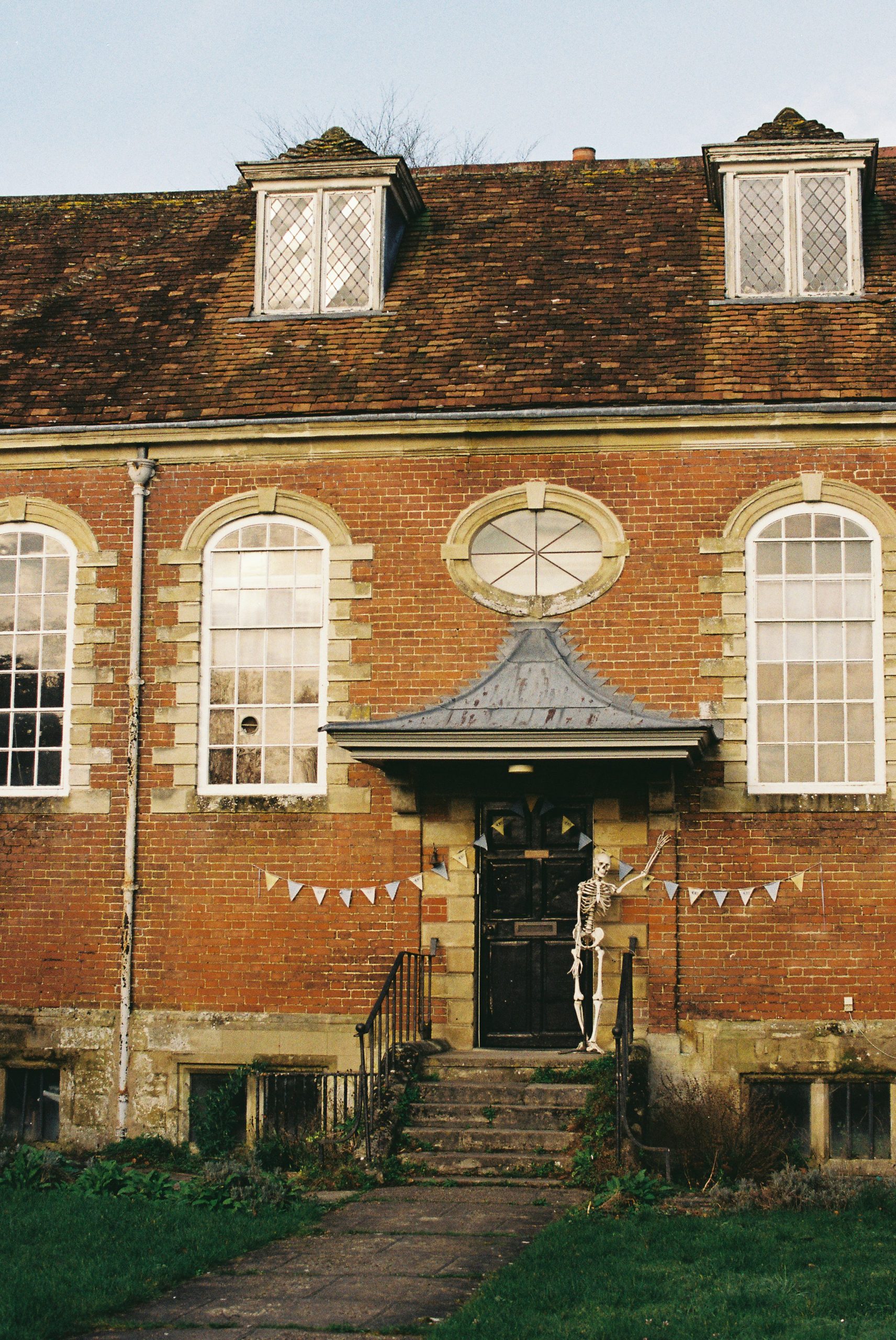 Skeleton decoration outside a brick house with festive bunting
