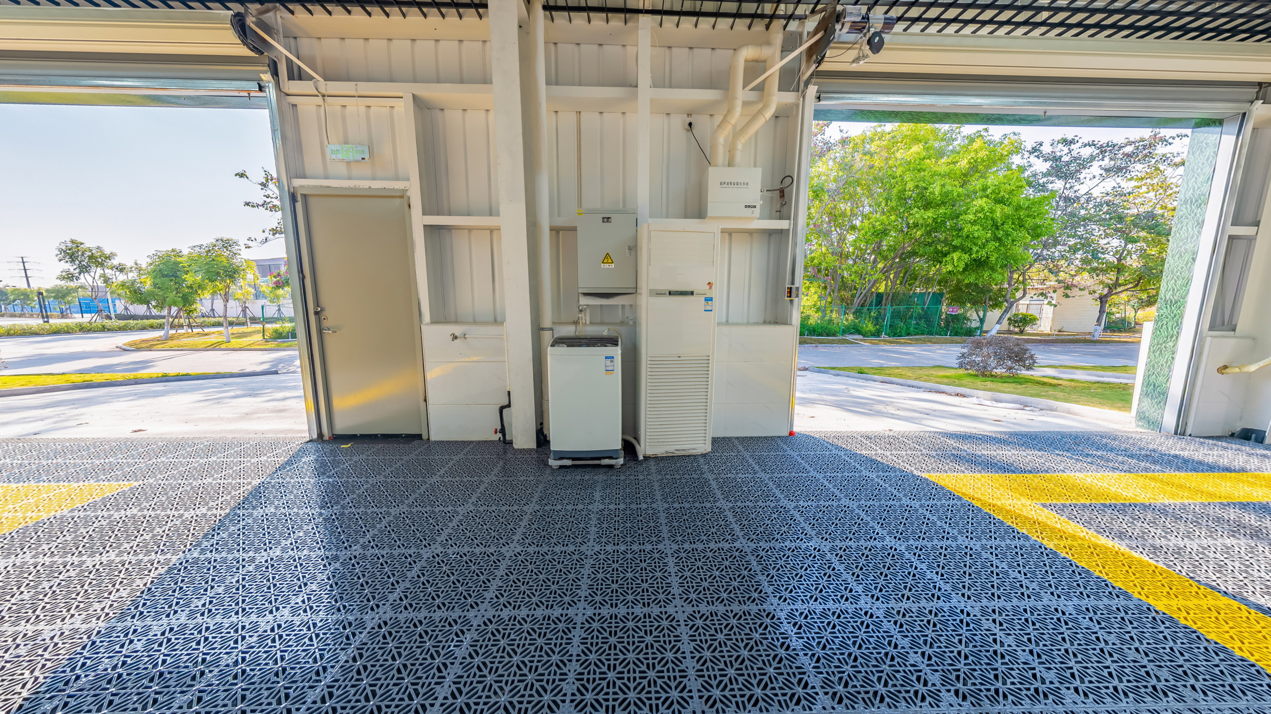 Spacious open garage with durable metal grid flooring and equipment setup facing outdoors.