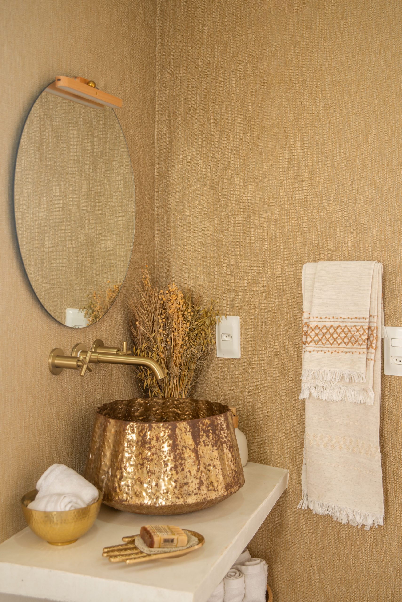 Stylish bathroom featuring brass fixtures, a round mirror, and modern decor.