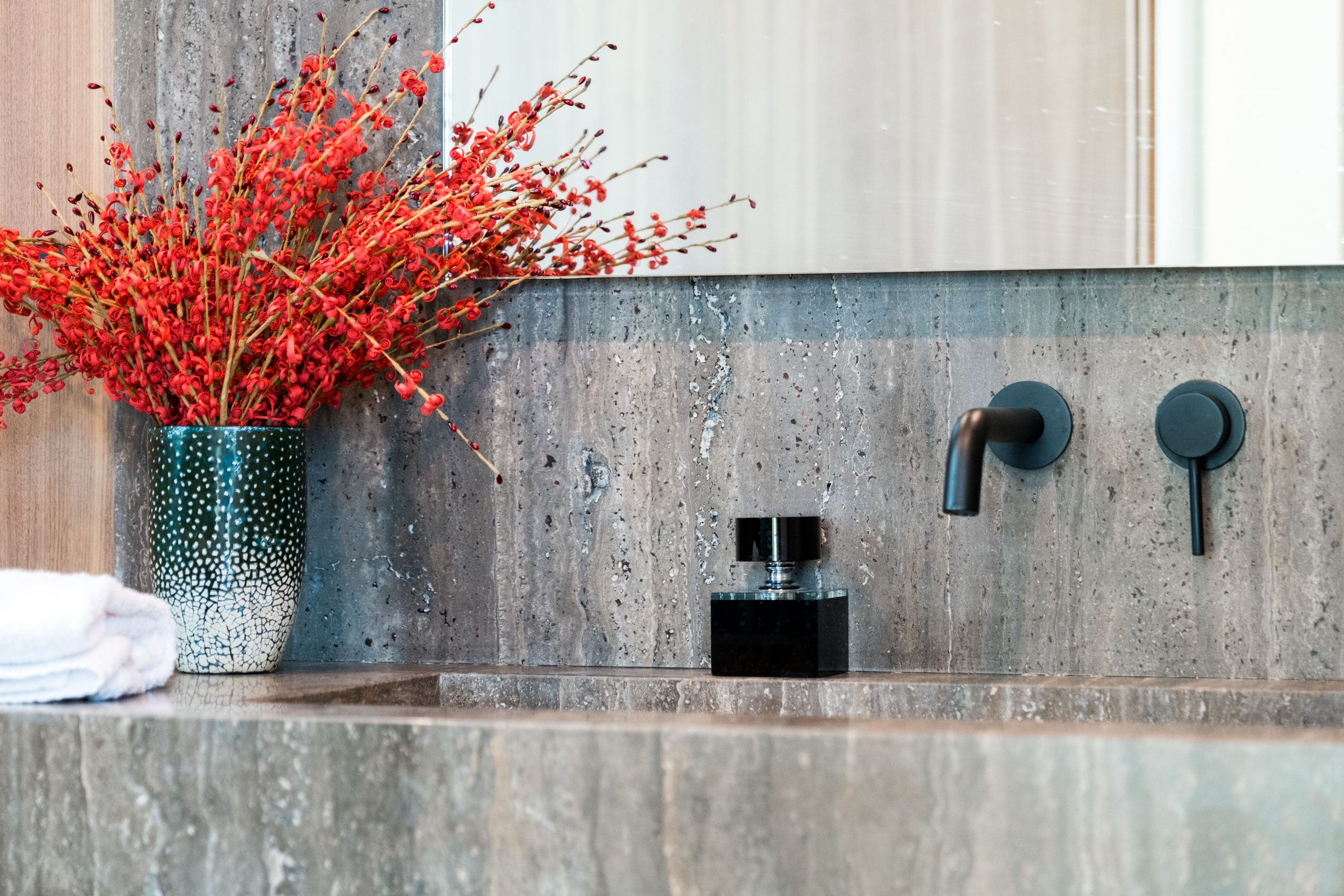 Stylish bathroom with modern fixtures and vibrant red floral arrangement.