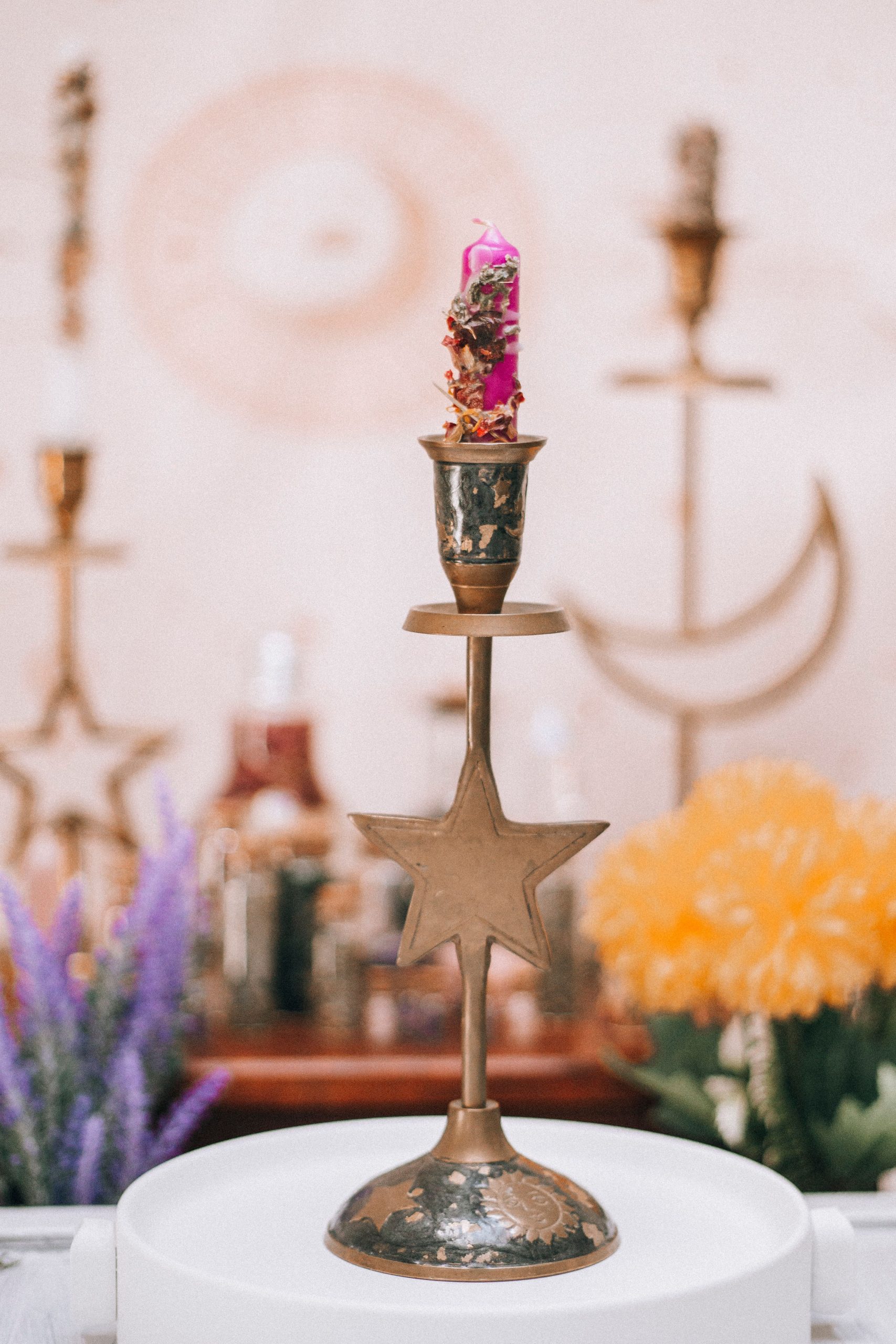 Stylish boho brass candle holder adorned with flowers on a whimsical backdrop.
