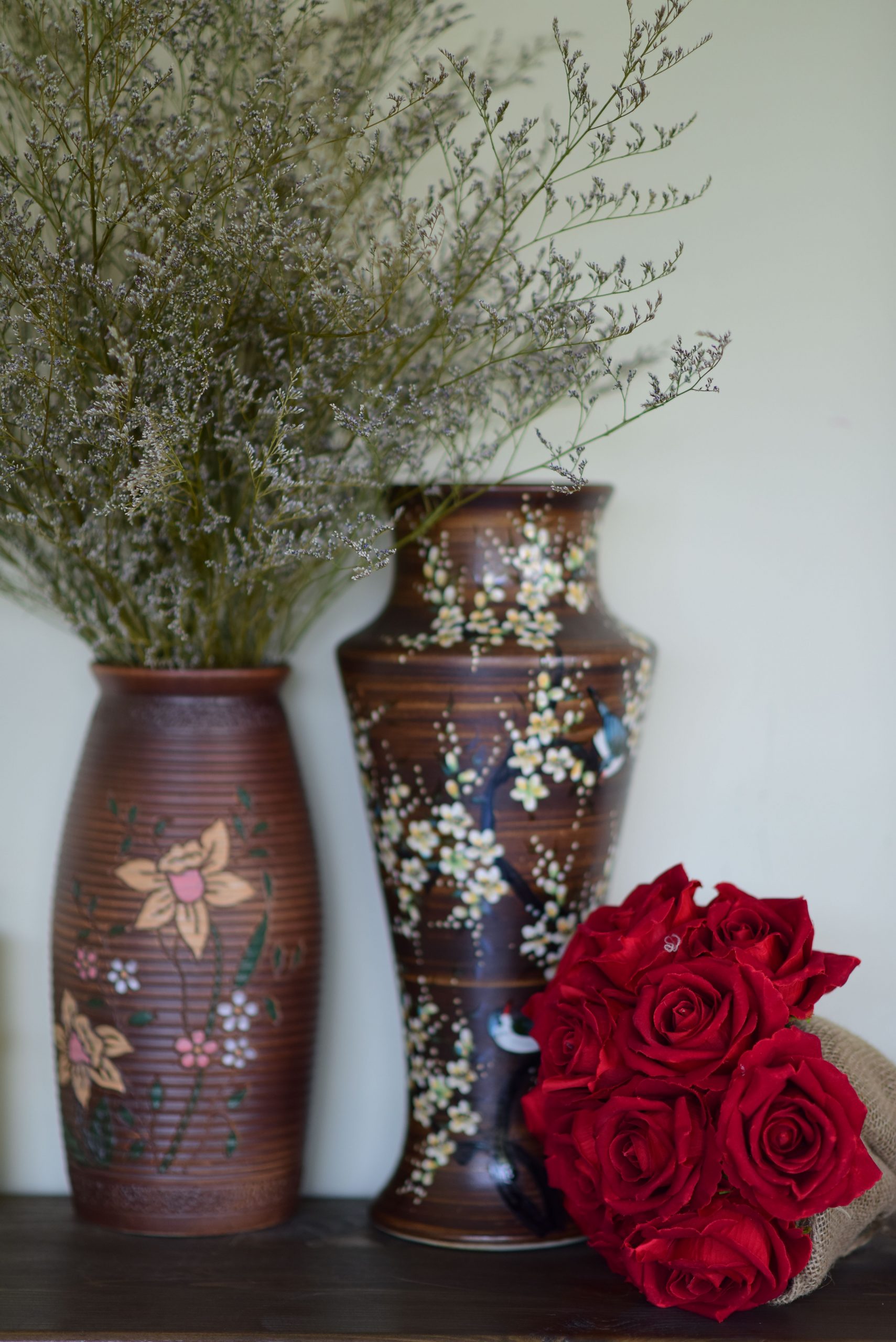 Stylish floral arrangement featuring vibrant red roses and intricately designed ceramic vases for home decor.
