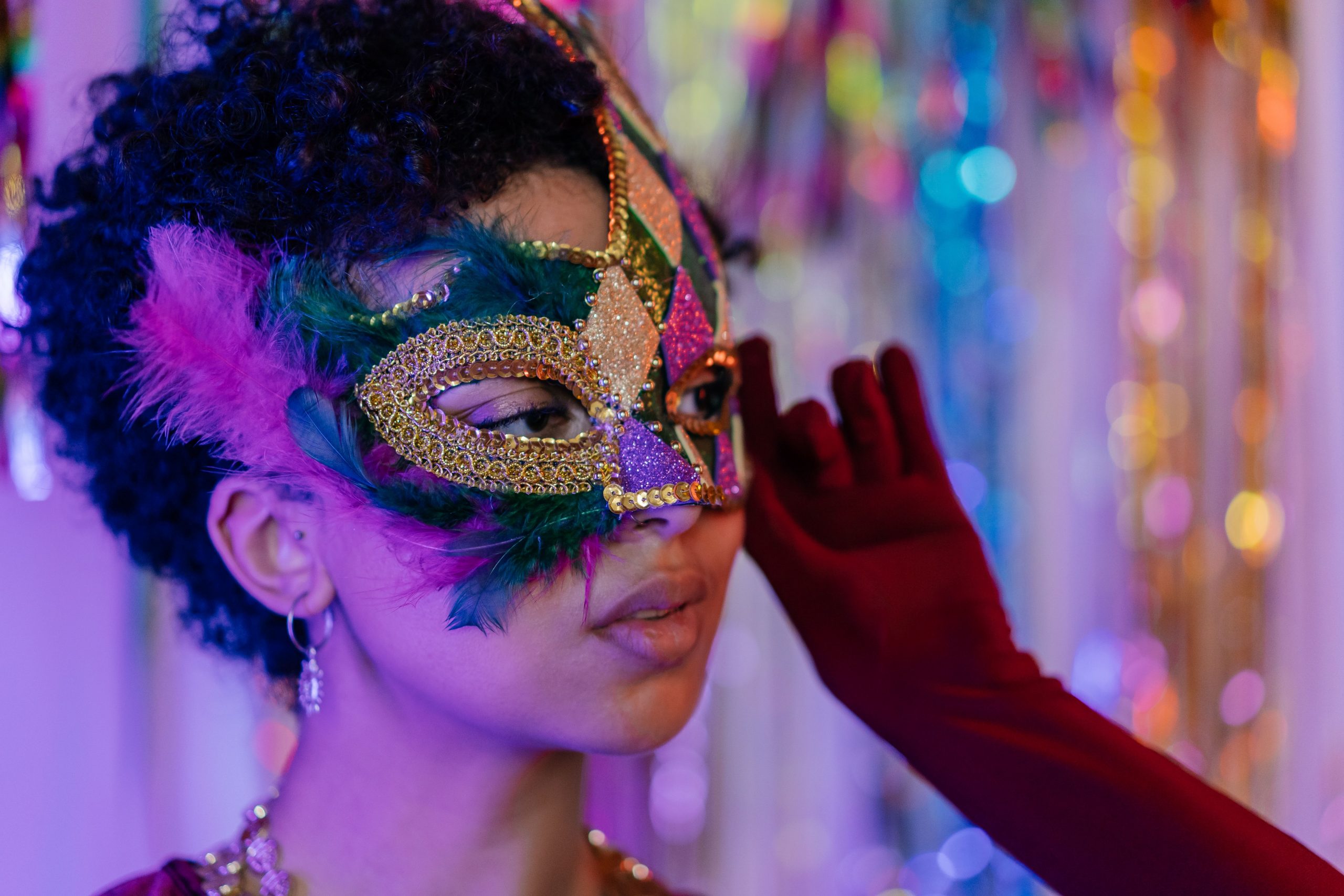 Vibrant masquerade mask with feathers worn at an indoor festive celebration.