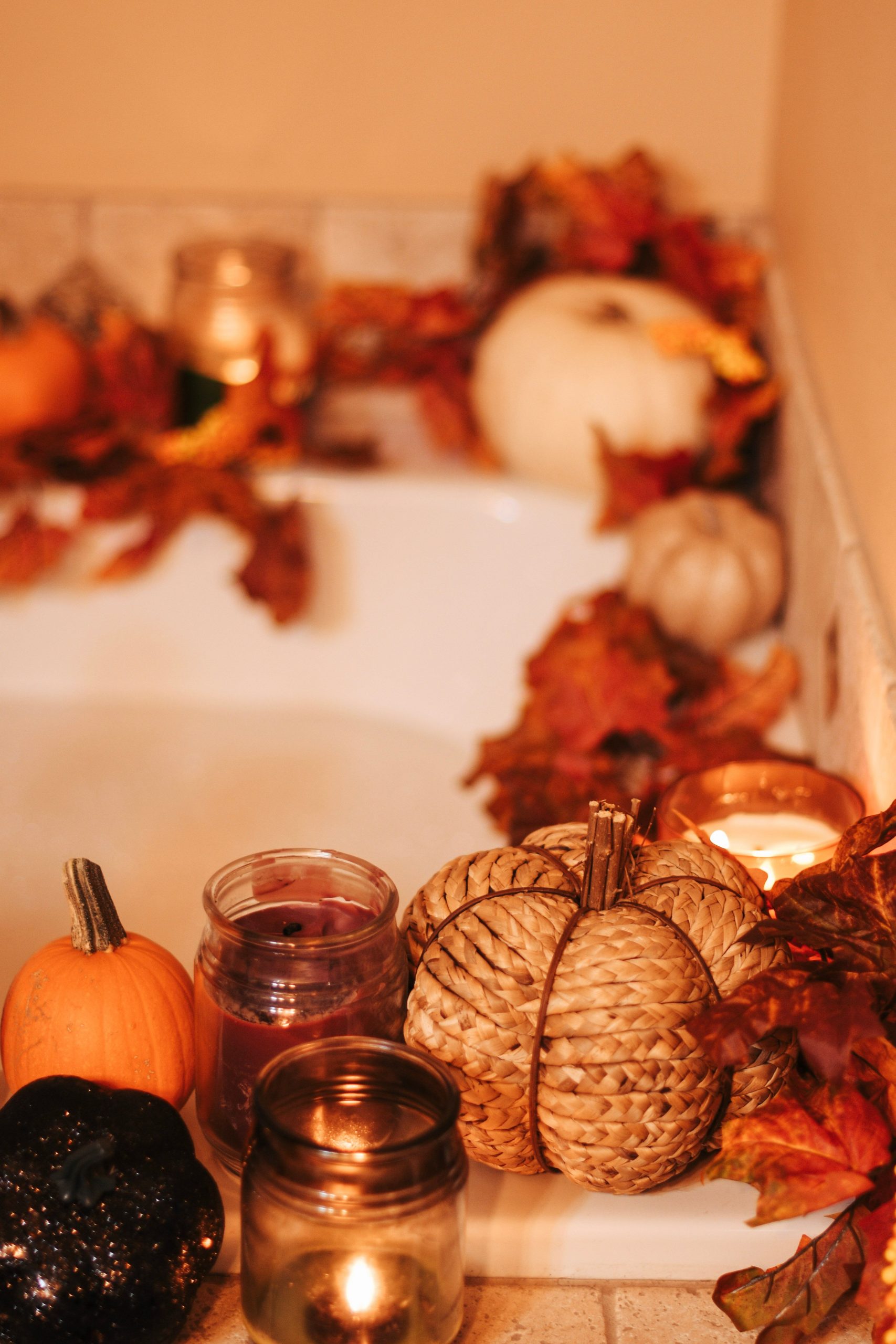 Warm and cozy bathroom scene with candles and pumpkins enhancing the fall atmosphere.