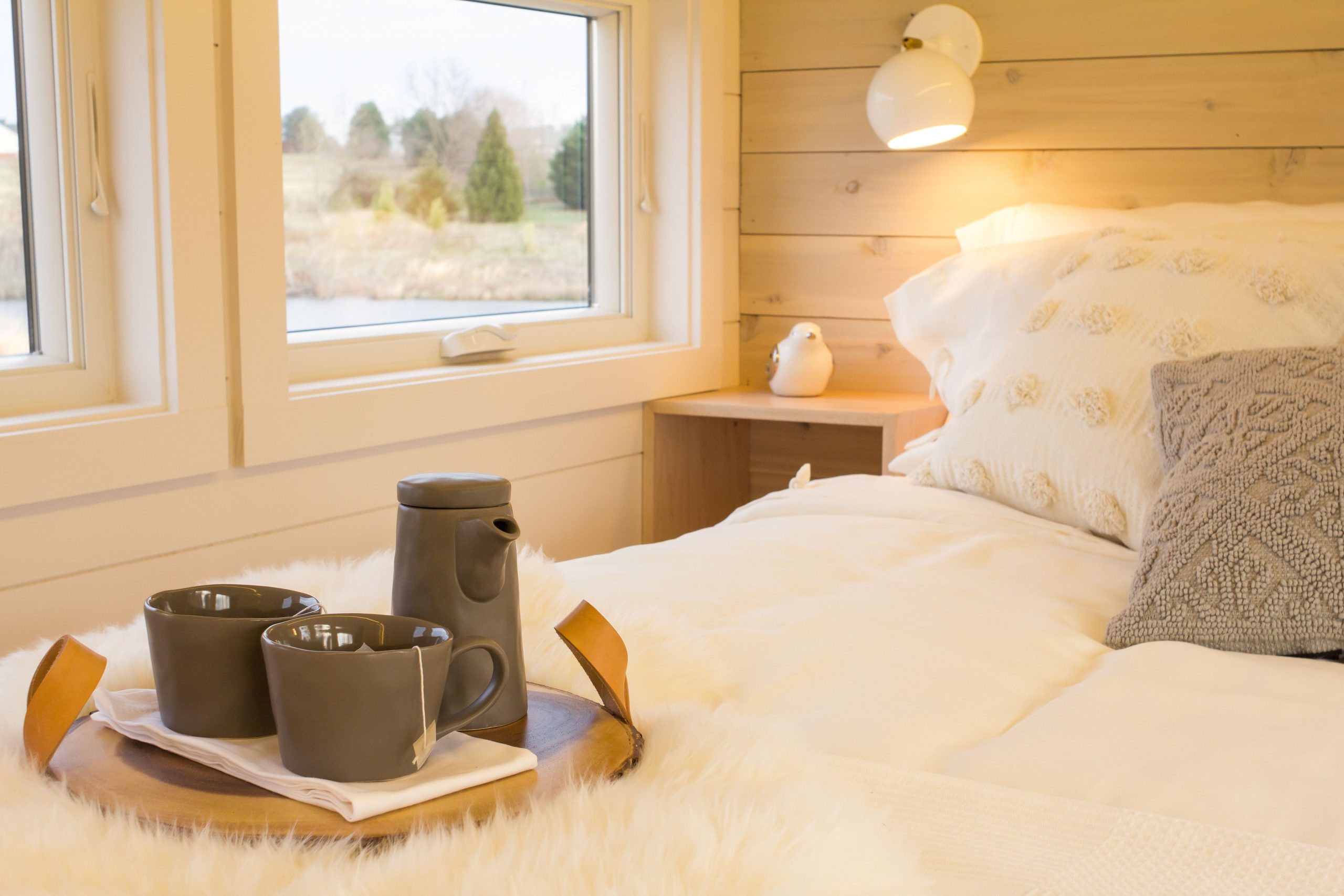 Warm and cozy Scandinavian-style bedroom with a tea setup on a wooden tray, perfect for relaxation.