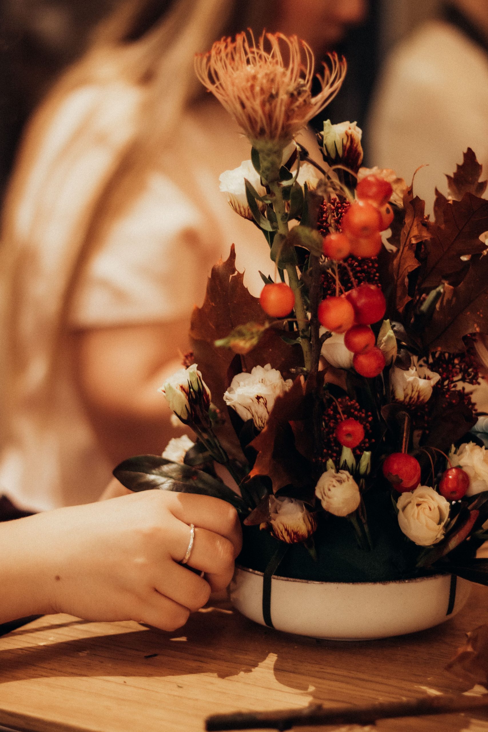 Warm autumn floral arrangement in a bowl with vibrant orange and red accents, evoking a cozy atmosphere.