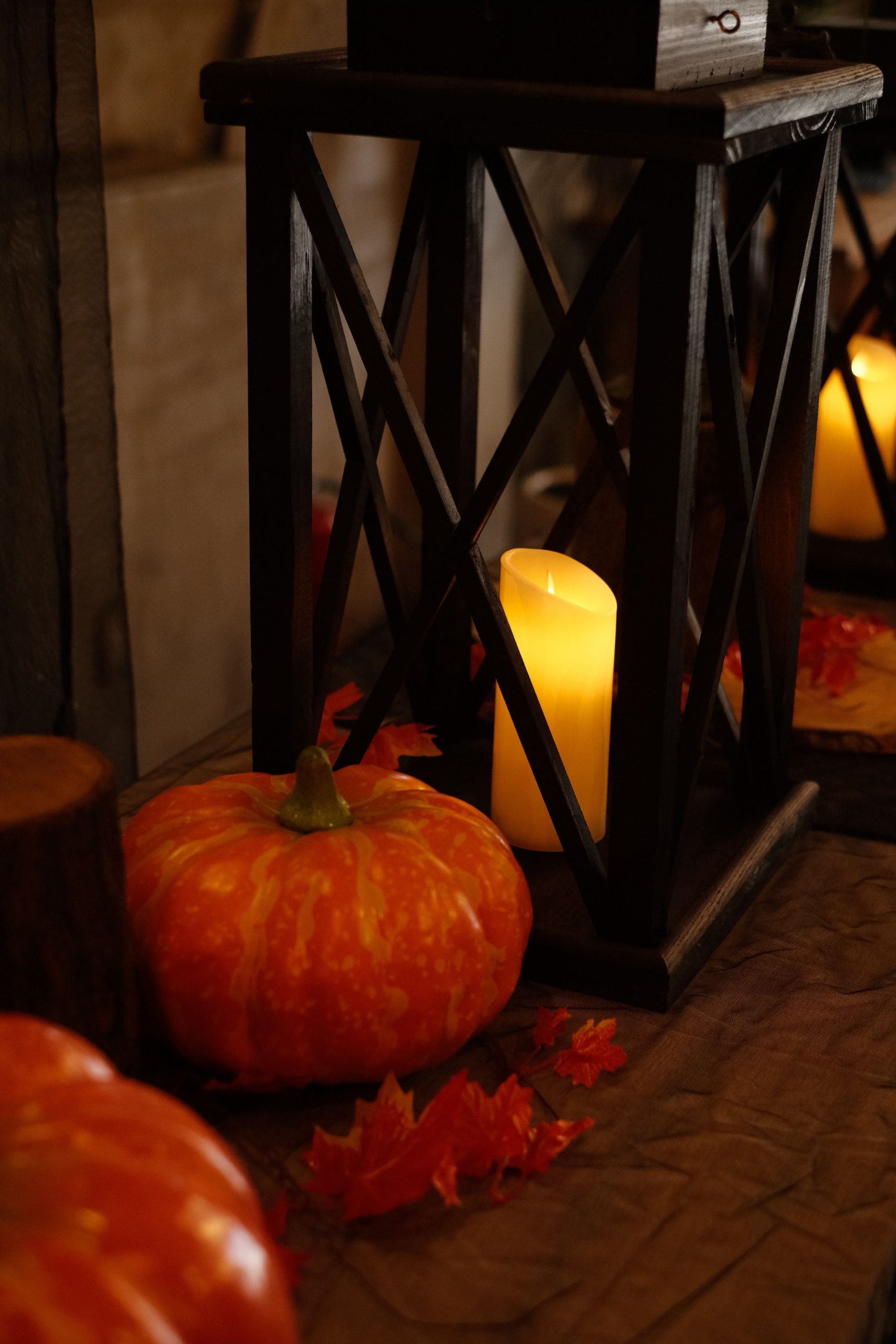 Warm autumn scene with pumpkins and candles in a rustic lantern setting, perfect for fall decor.