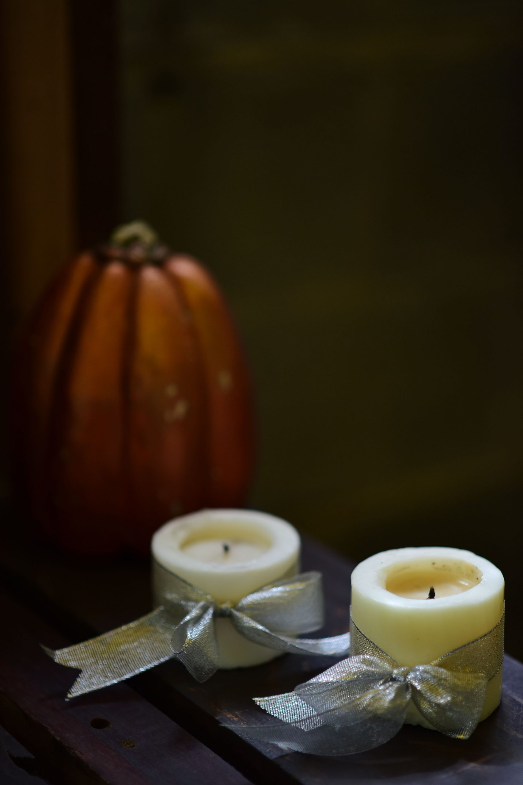 Warm autumn setting with candles and pumpkin on a wooden surface.