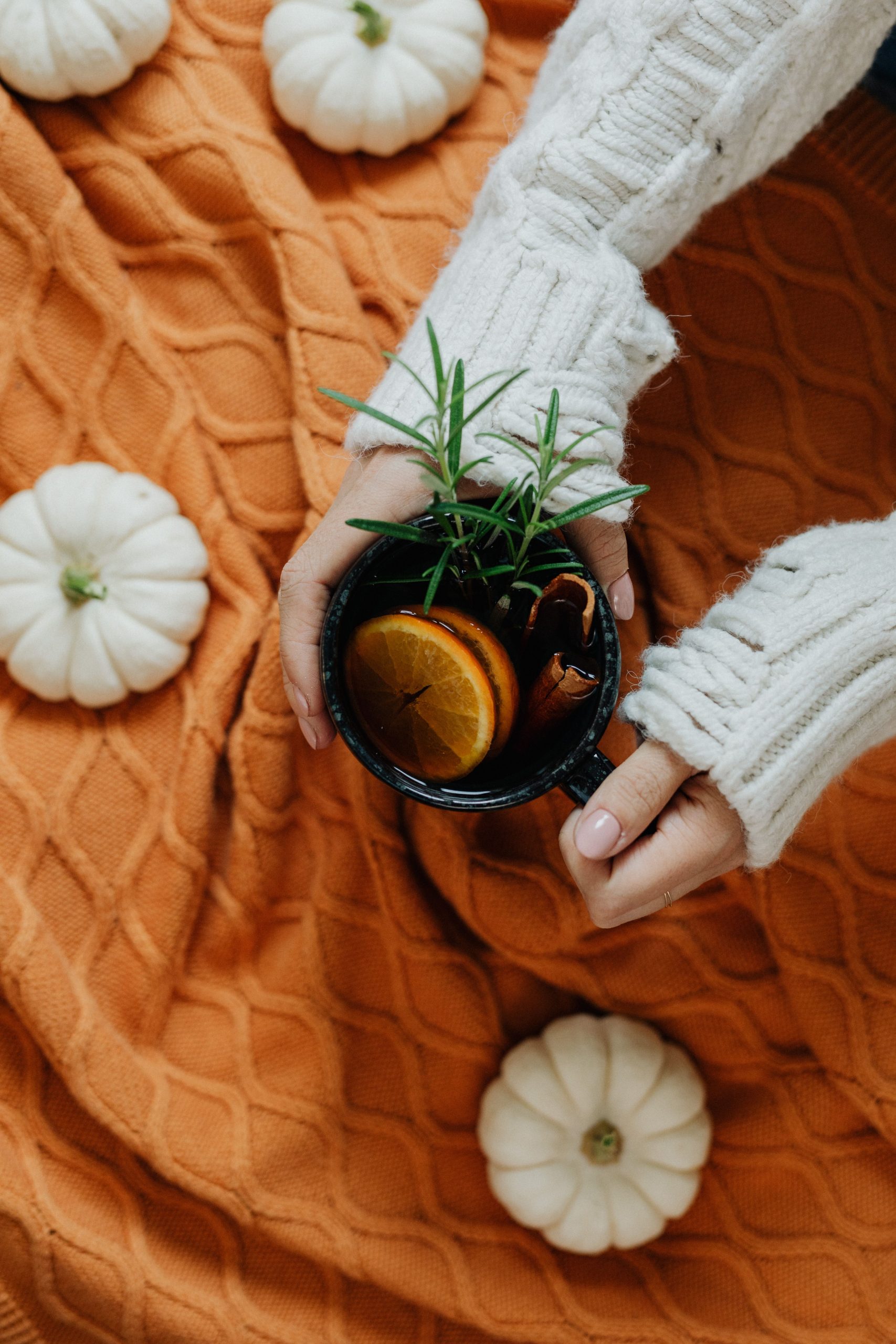 Warm autumn setup with tea, pumpkins, and cozy blanket for a relaxing season vibe.