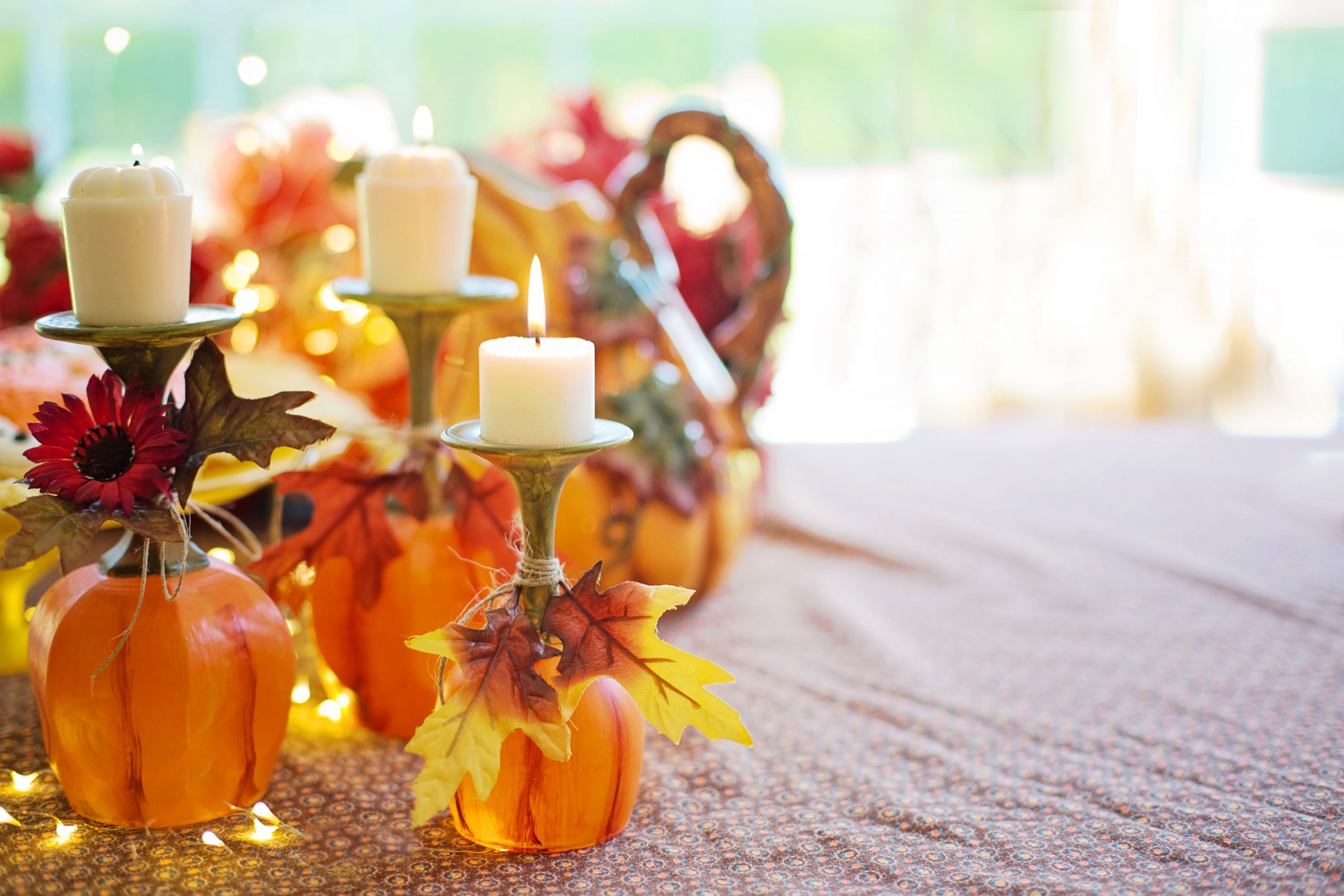 Warm autumn table decor featuring pumpkins, candle holders, and fall leaves.