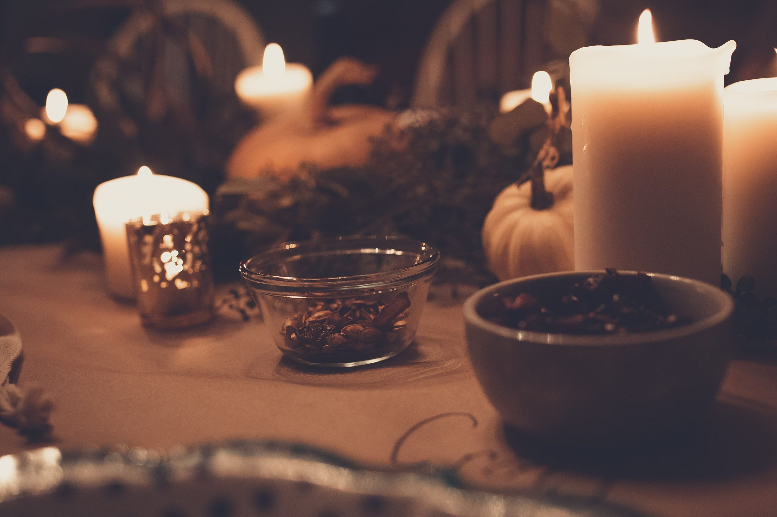 Warm autumn table setting with candles, pumpkins, and bowls, creating a cozy atmosphere.