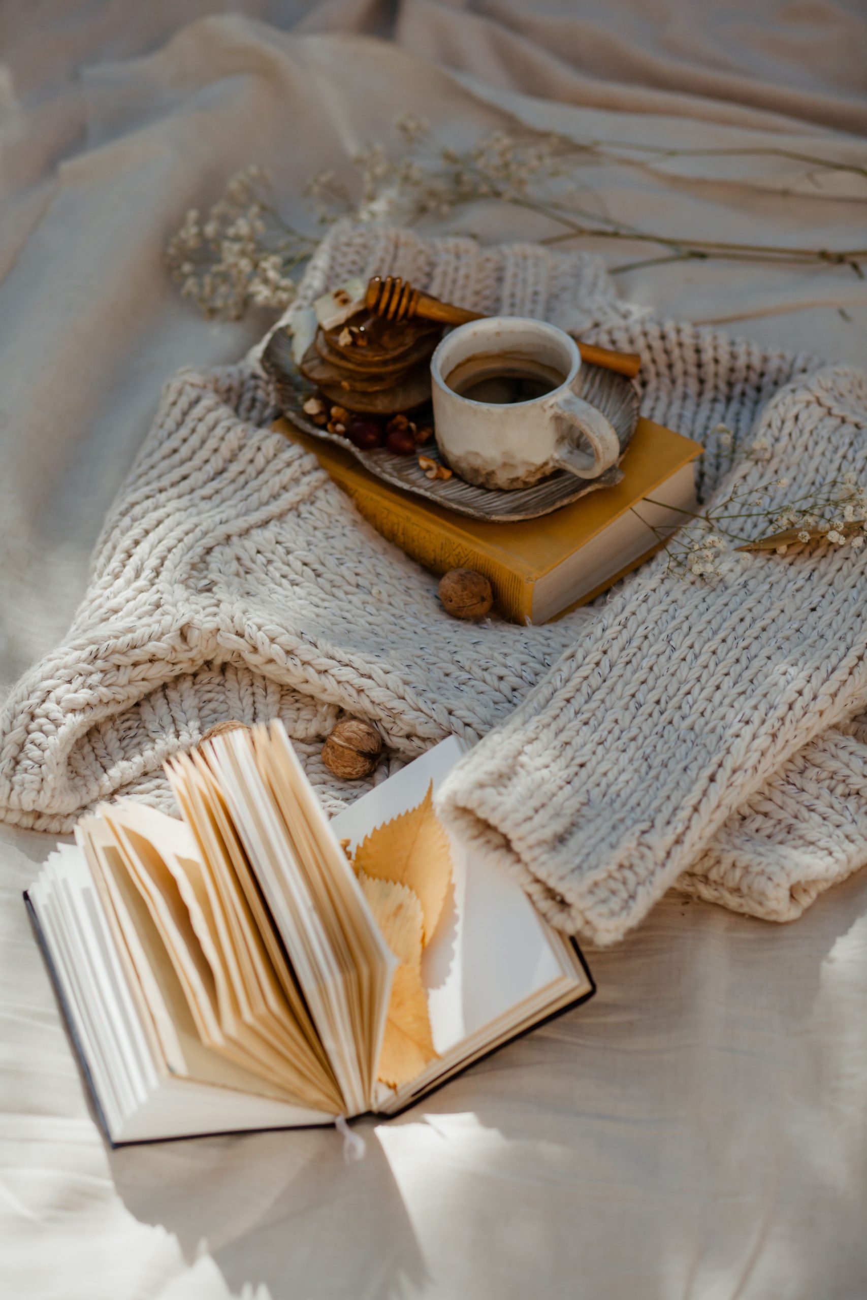 Warm cozy scene with coffee and an open book on knitted fabric, perfect for autumn inspiration.