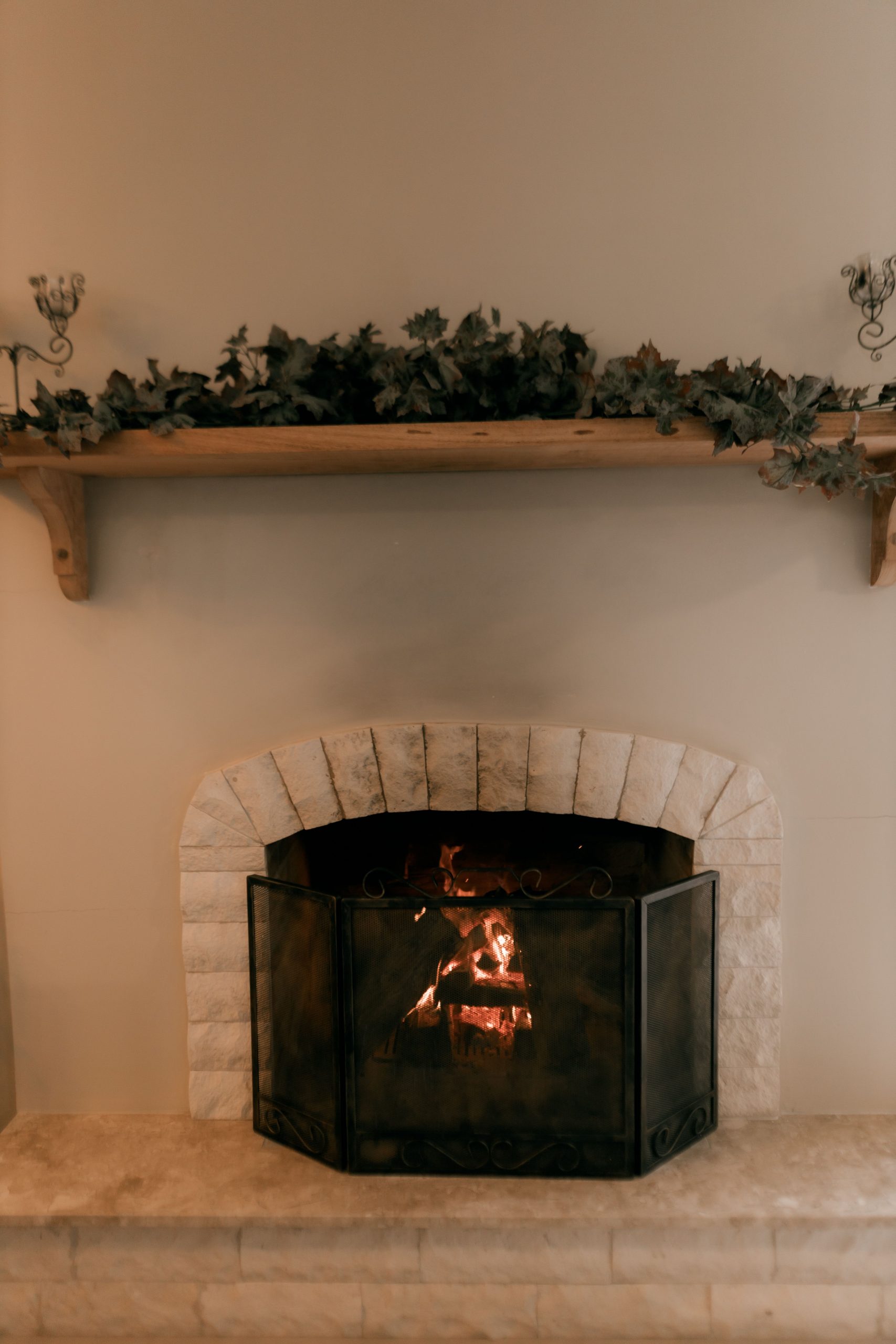 Warm glowing fireplace with a rustic mantel decorated for a cozy atmosphere.