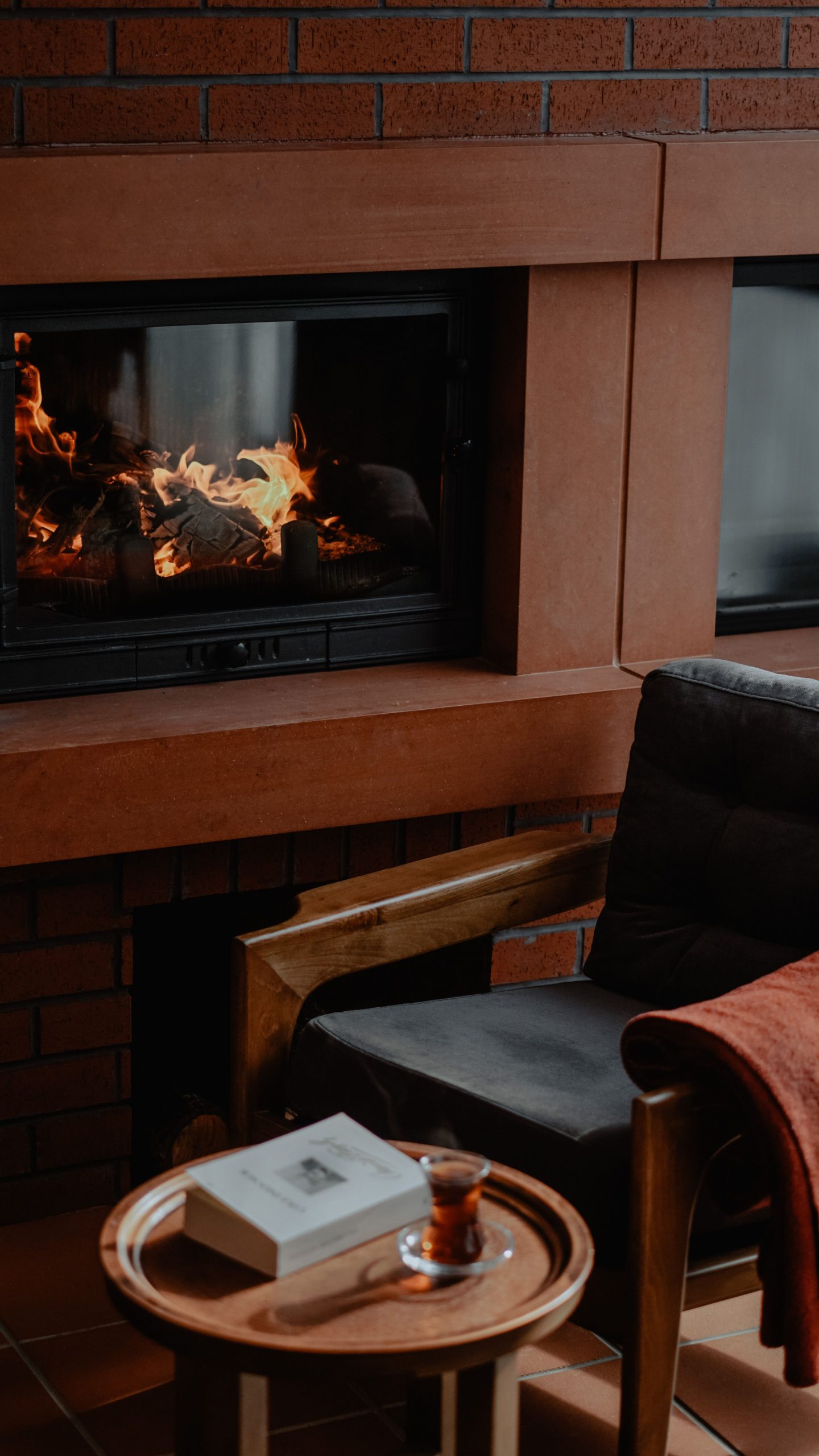 Warm living room scene with a fireplace, armchair, and a book for a cozy ambiance.