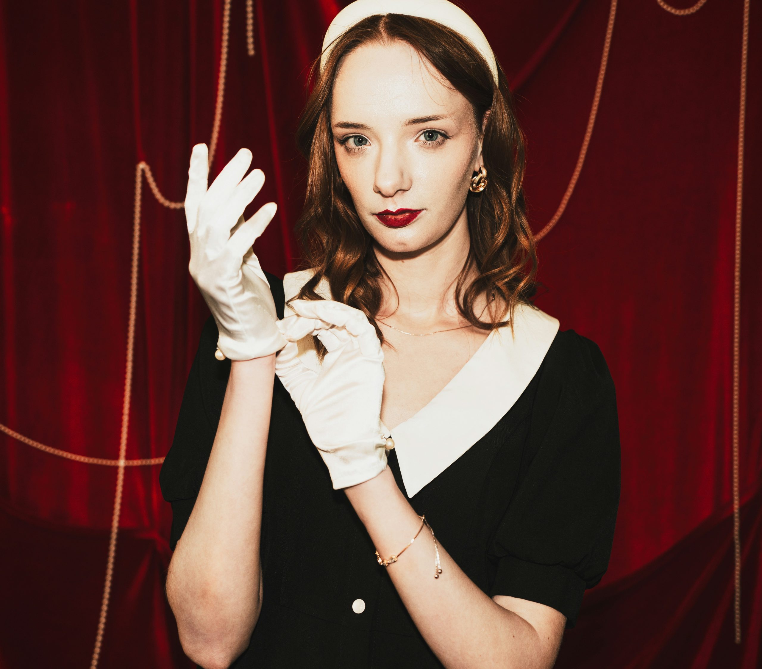Woman in vintage dress and gloves adjusts her hand