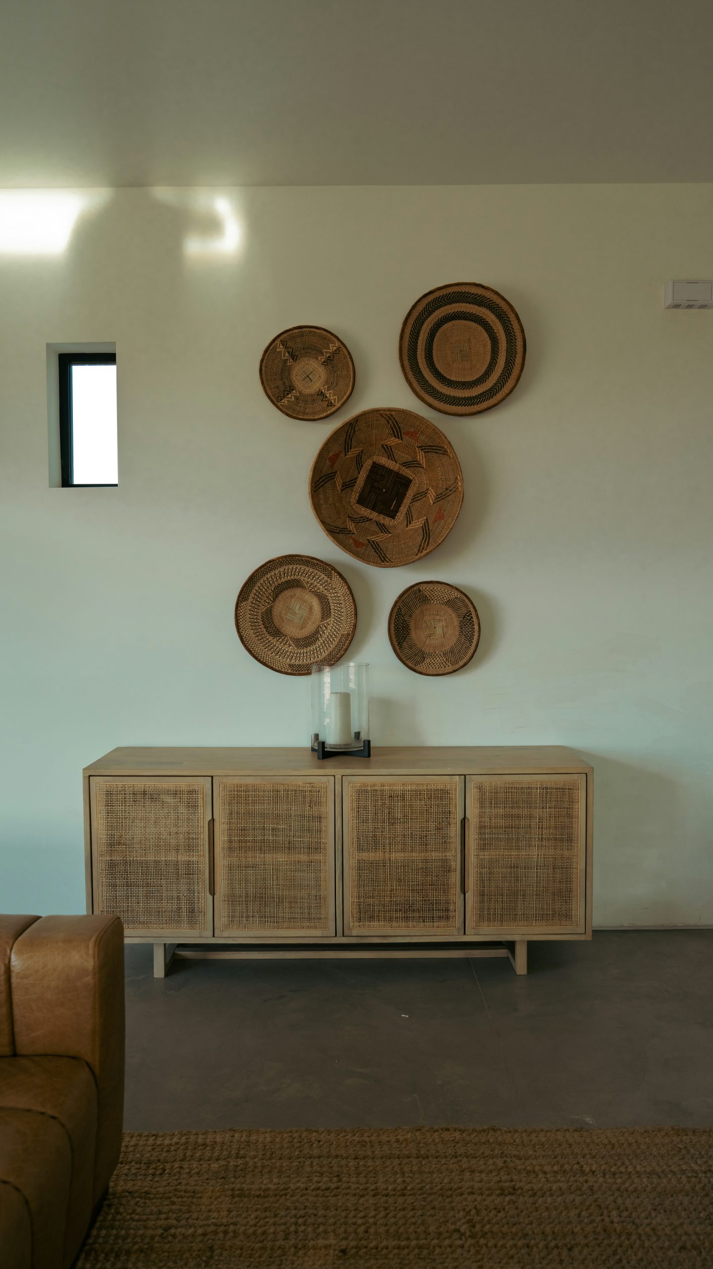Woven baskets decorate a wall above a wooden sideboard