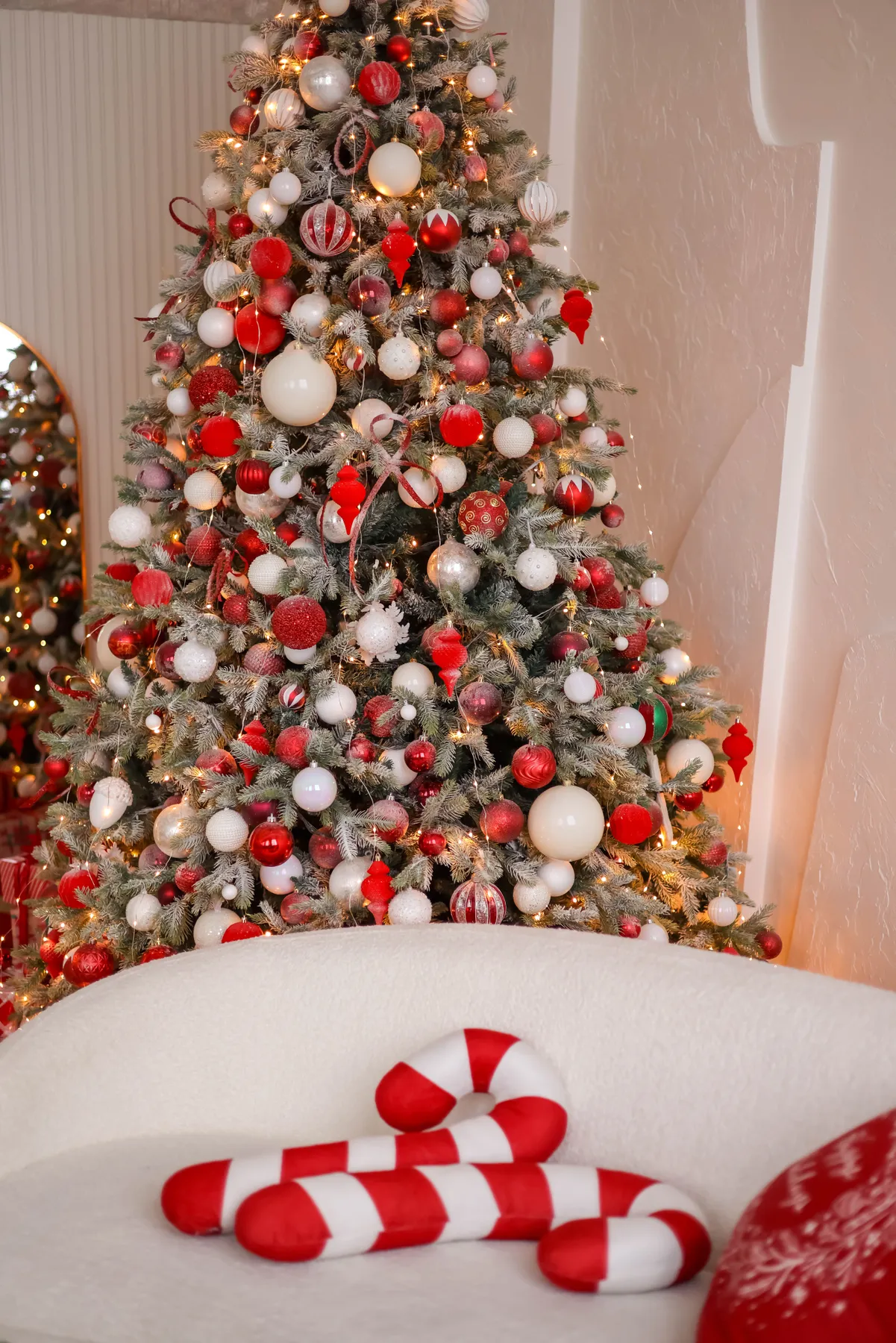 A beautifully decorated Christmas tree with candy cane pillows in a cozy living room.