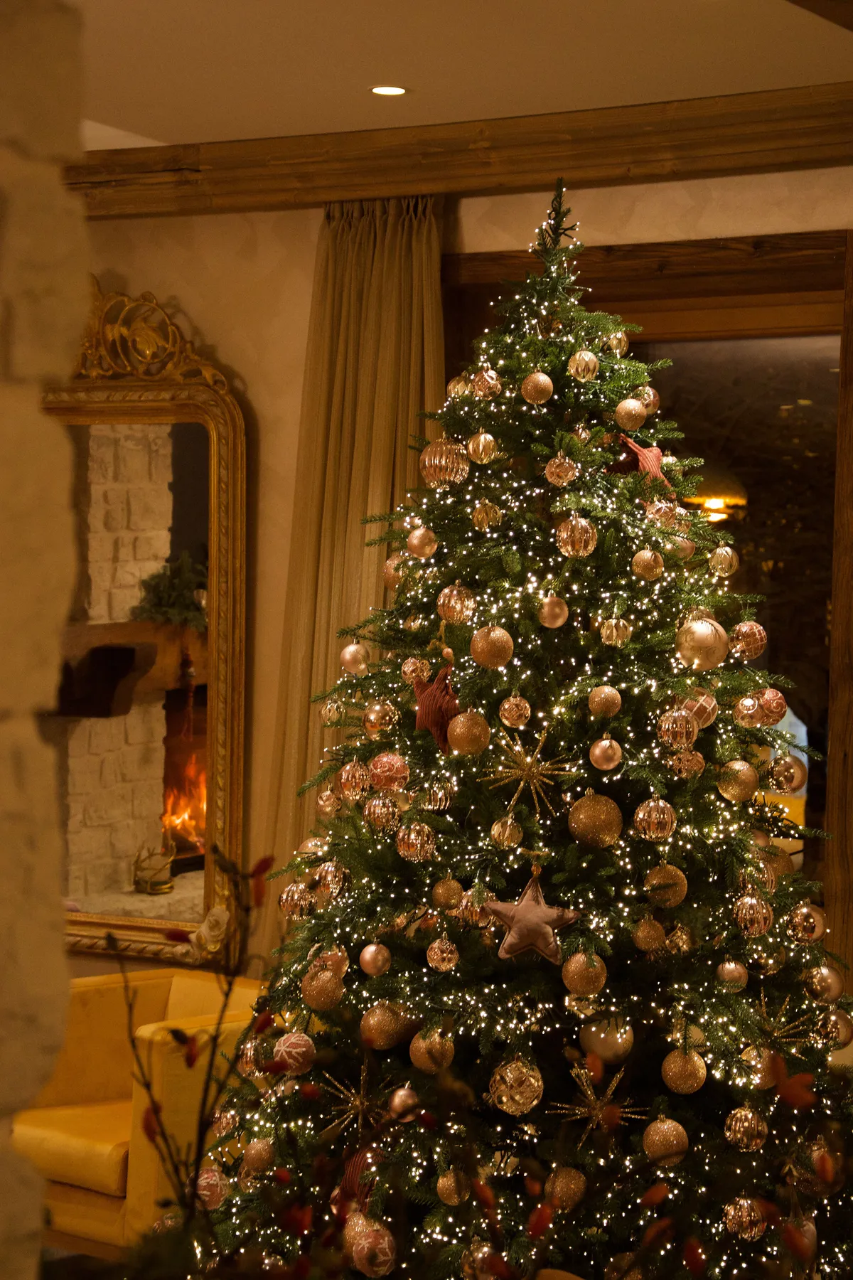 A beautifully decorated Christmas tree with lights and ornaments in a warm and cozy living room.