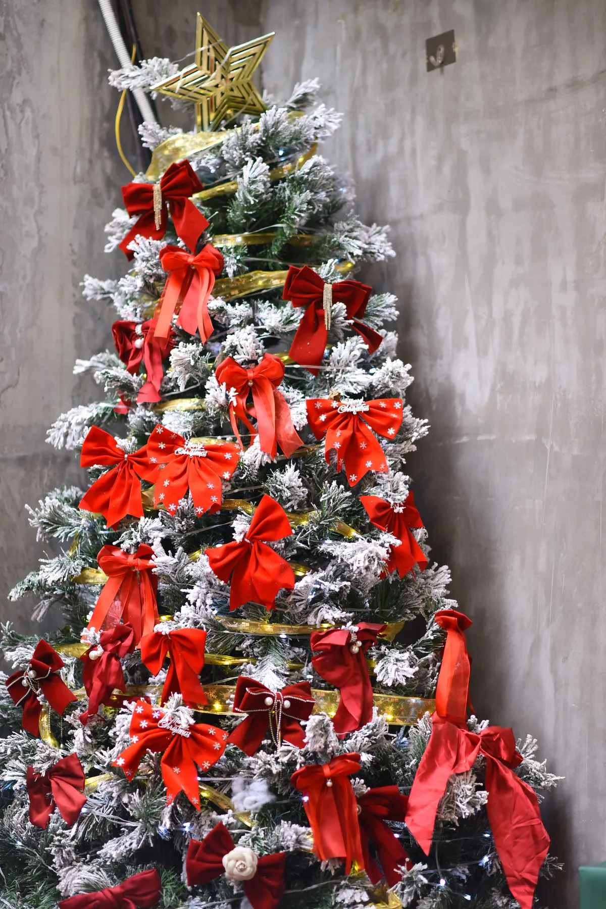 A beautifully decorated Christmas tree with red bows and a star topper indoors, perfect for holiday celebrations.