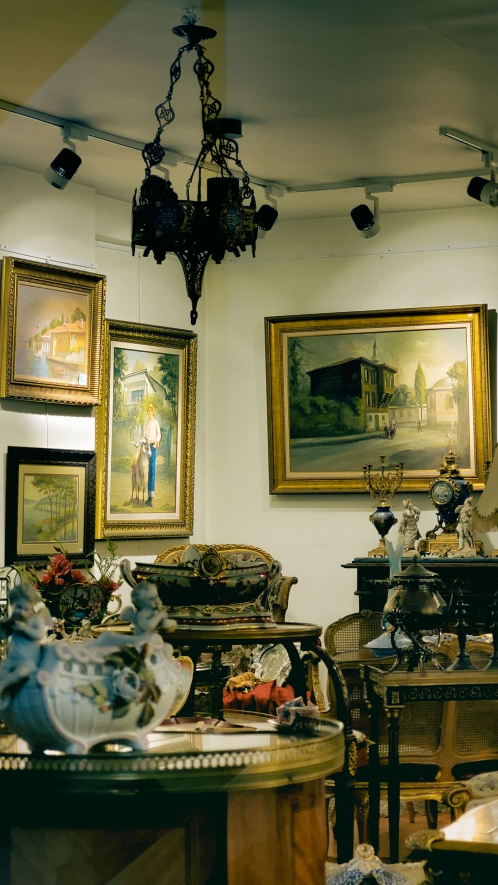 A beautifully decorated room with paintings, antique furniture, and a chandelier, creating a vintage interior design vibe.