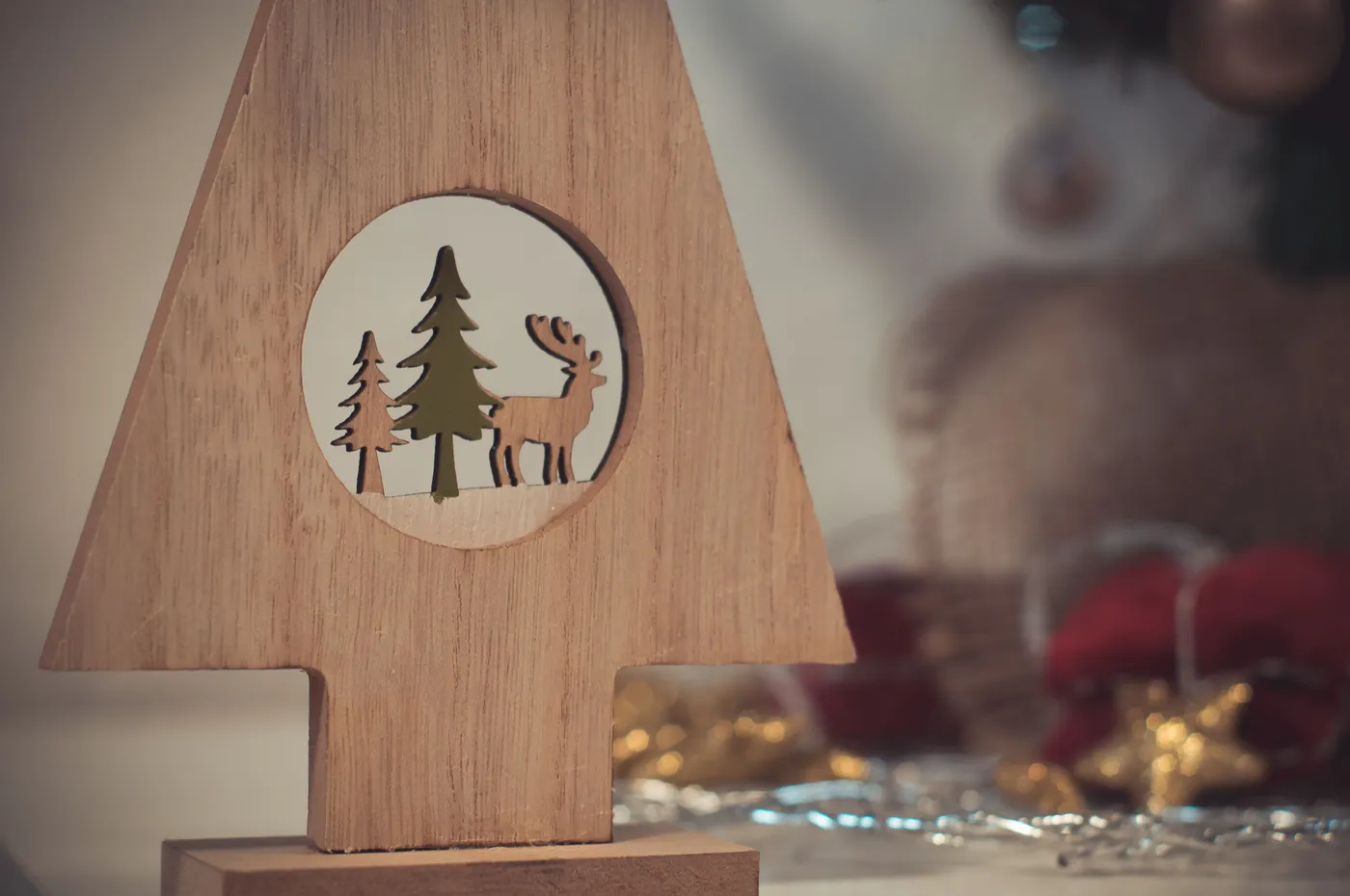 A charming wooden Christmas decoration featuring a reindeer and pine trees, perfect for holiday decor.