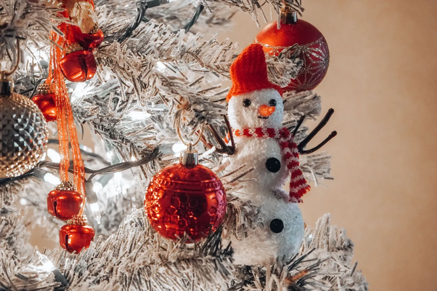 A close-up of a Christmas tree with red ornaments and a snowman decoration, evoking holiday cheer.
