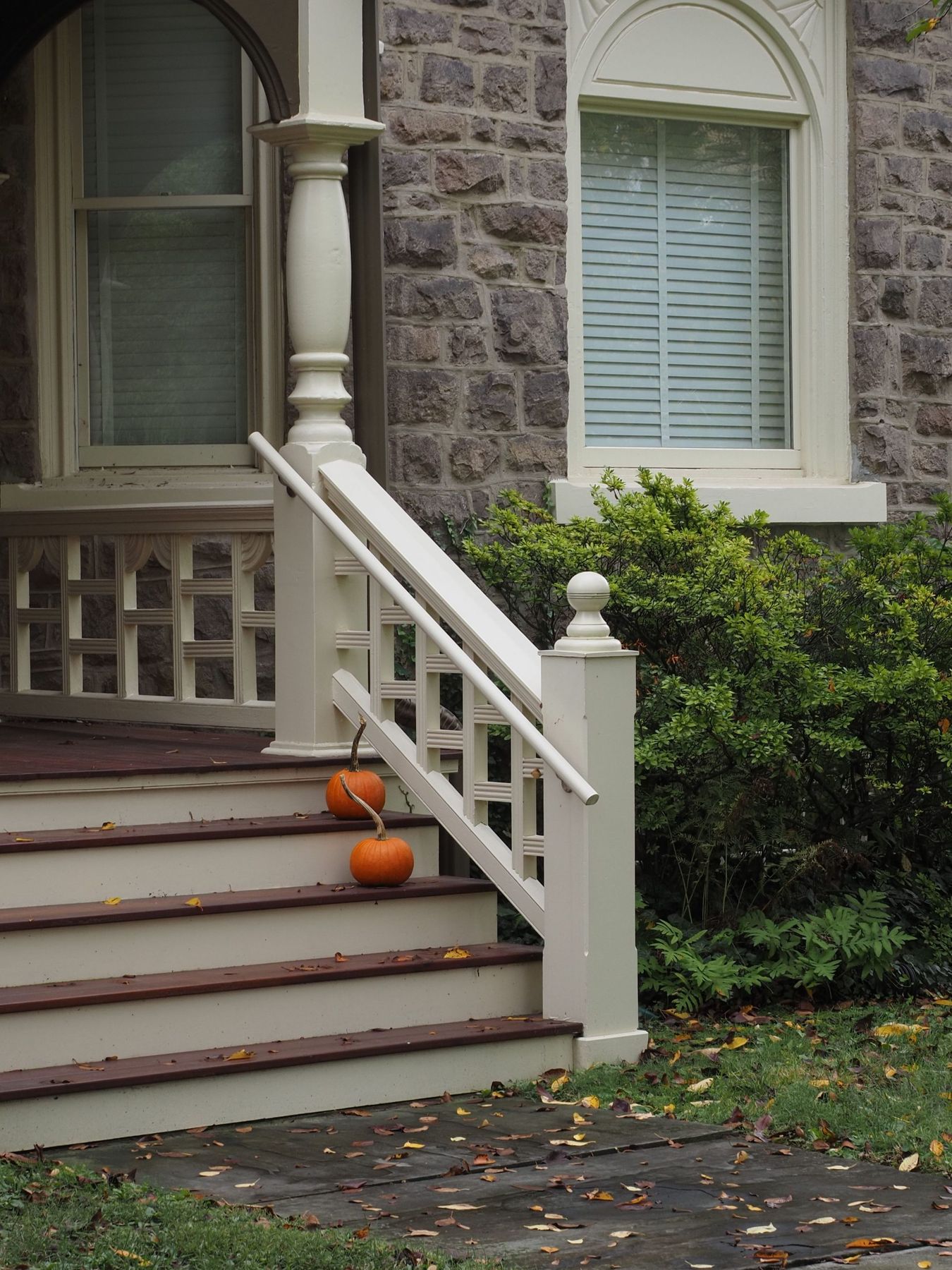 A cozy stone house porch decorated with pumpkins and fall leaves ideal for seasonal themes.